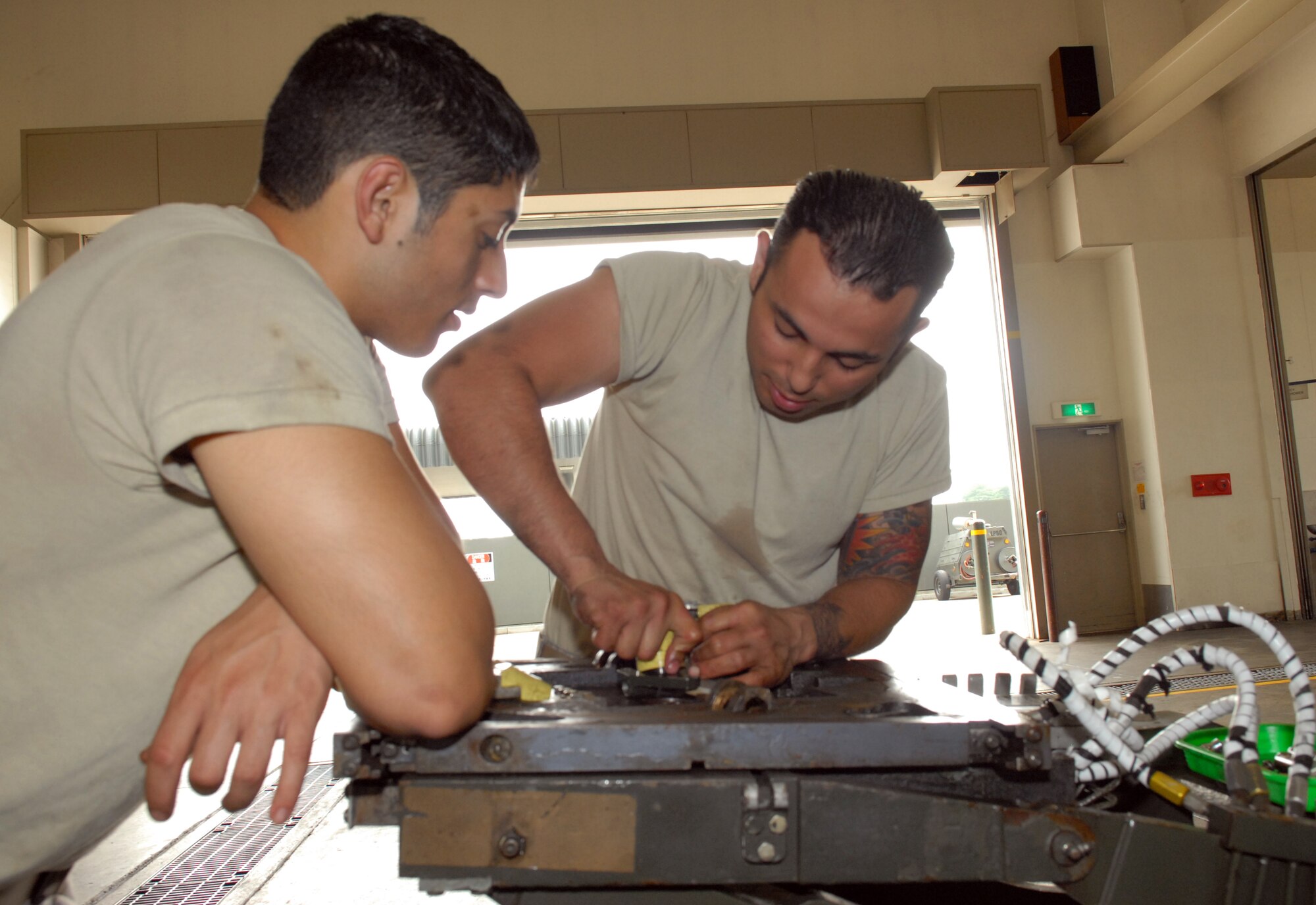 MISAWA AIR BASE, Japan -- Airman 1st Class Johnathan Gomez and Alfredo Sandoval-Alvarez, 35th Maintenance Squadron Aerospace Ground Equipment apprentices, repair tilt cylinders on a MJ1B bomb lift July 23 in the AGE maintenance building. The MJ1B bomb lift is the primary vehicle used to load bombs and other munitions on the F-16 Fighting Falcon. (Air Force photo/Staff Sgt. Phillip Butterfield)