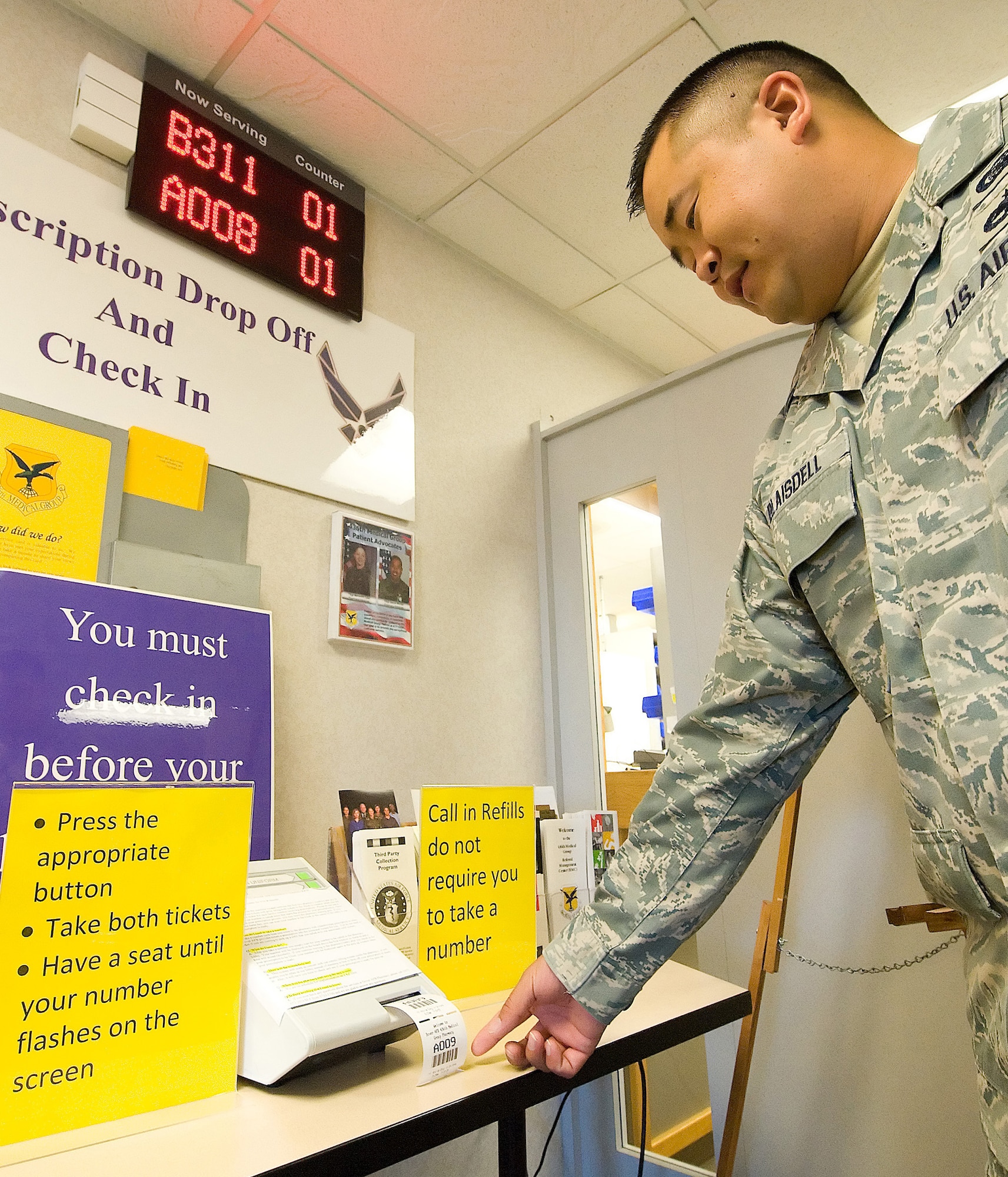 Tech. Sgt. Jason Blaisdell, 436th Communications Squadron, pulls a ticket from the number ticket dispenser. The 436th Medical Group pharmacy began using the new system to help keep track of patients in a more organized manner, making it easier for patients waiting for prescriptions. (U.S. Air Force photo/Tom Randle)