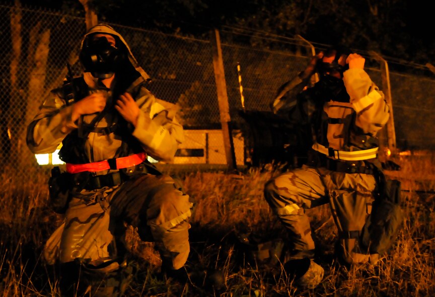 RAF MILDENHALL, England – Airman 1st Class Cody Seymour and Staff Sgt. Marc Bakker, both from the 100th Civil Engineer Squadron, don gas masks during a phase-two exercise July 22.  Airman Seymour and Staff Bakker are both members of the damaged airfield reconnaissance team that sweeps the runway area after any simulated attack to check for damage or unexploded ordinance.  (U.S. Air Force photo by Staff Sergeant Christopher L. Ingersoll)