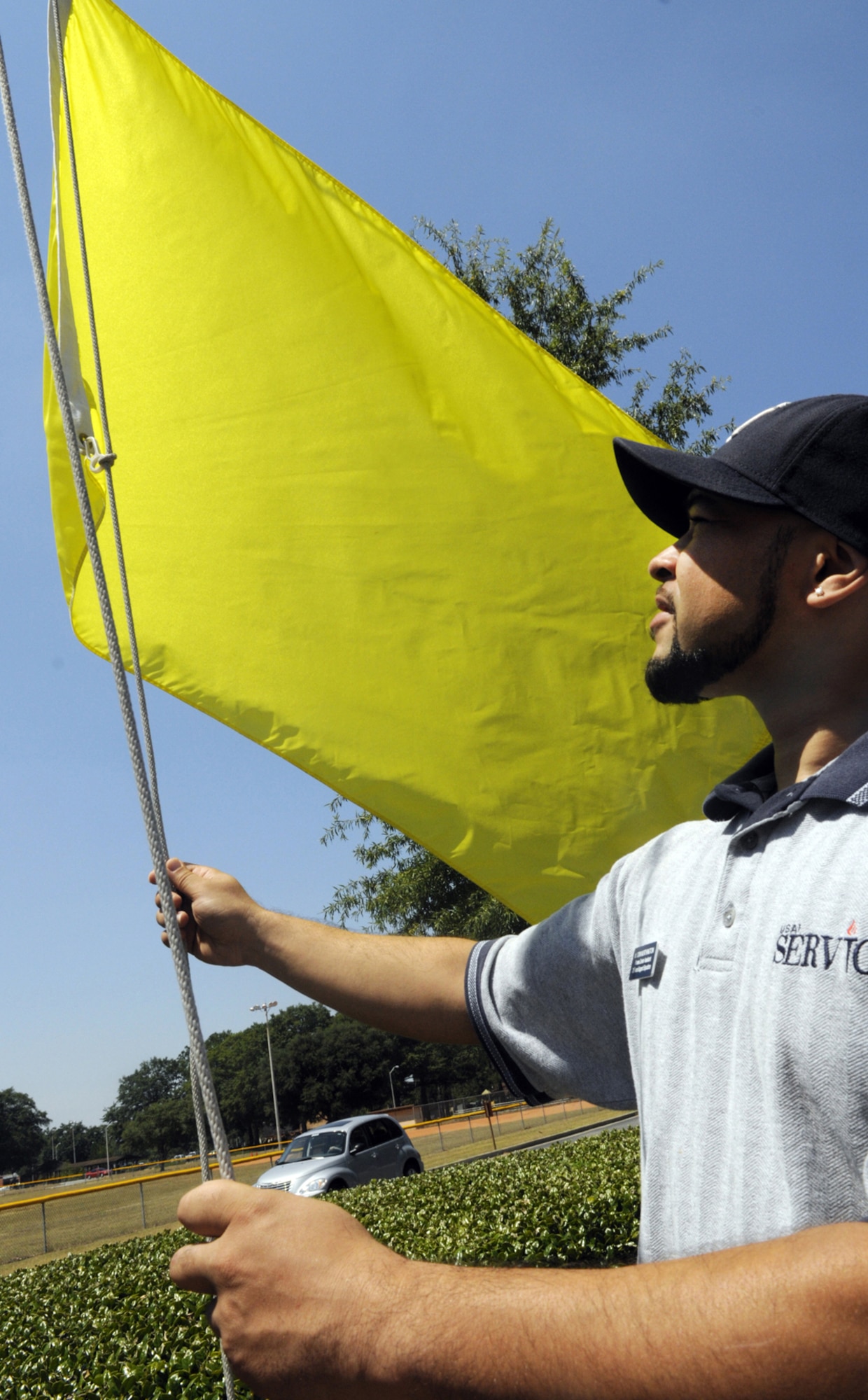 Don Worthington, Fitness Center assistant, raises a yellow heat index flag July 20 to indicate the heat conditions at that time. The yellow flag represents a recommendation of a 40/20 minutes work/rest cycle for moderate work, and a 30/30 work/rest cycle for hard work. U. S. Air Force photo by Sue Sapp     