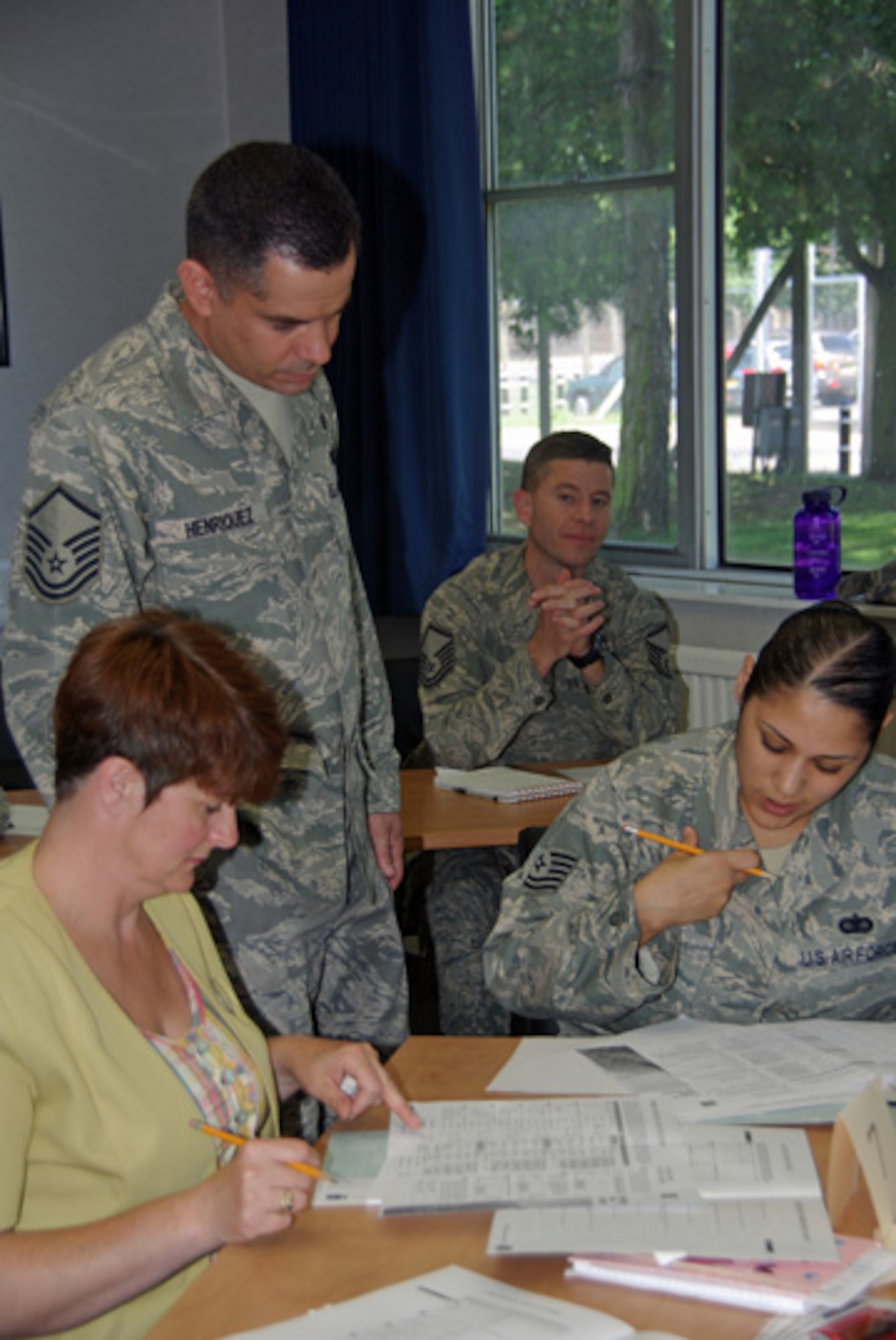 RAF Mildenhall, ENGLAND – Master Sgt. Erasmus Henriquez, 352nd Special Operations Group assists Beth Cooper, 100th Force Support Squadron, and Tech. Sgt. Arlene Lee, 100th Communications Squadron, as they complete their score sheets during a group dynamics exercise recently held at the Professional Development Center here.  The exercise which prides itself on hands-on learning with no slides was well received by participants. The next class is Aug. 4. Anyone interested in participating can contact the PDC at 238-5933. (U.S. Air Force photo by Tech. Sgt. Marelise Wood)