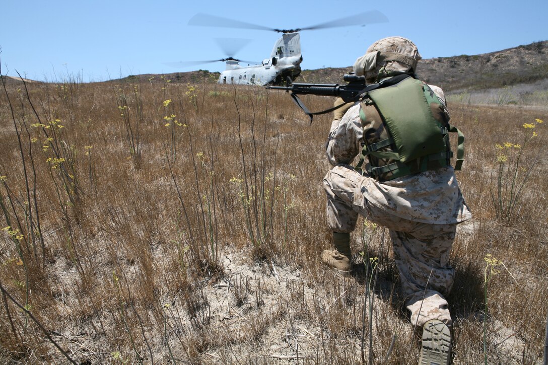 A Marine from the 4th Light Armored Reconnaissance Battalion posts security while members of the battalion load a simulated casualty. The 4th LAR and Mainre Medium Helicopter Squadron 165 cooperated in a casualty evacuation excercise July 11 aboard Marine Corps Base Cmap Pendleton.