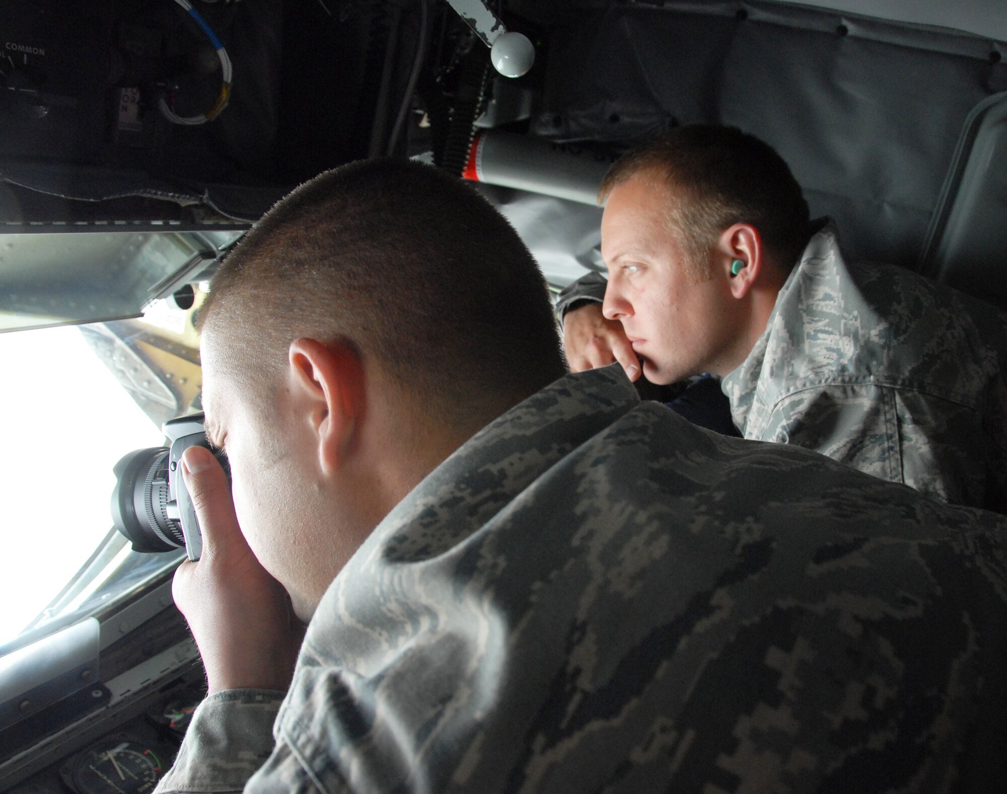 Tech. Sgt. Dana Rosso, 477th Fighter Group Aircraft Maintenance Squadron, takes a photo from the back of a KC-135 Stratotanker, as Staff Sgt. Eric Jagodzinski, 477th FG AMXS, observes.  Tech. Sgt. Rosso and Staff Sgt. Jagodzinski were two of 14 personnel from the 477th FG and 3rd Wing who flew on a KC-135 Stratotanker orientation flight July 14. The crew from the 434th ARW came up to Elmendorf Air Force Base from Grissom Air Reserve Base, Indiana to support the 477th FG's first-flying Unit Training Assembly in July.  They flew several personnel and spouses from the 477th FG and the 3rd Wing here on orientation flights, showcasing the KC-135 and F-22 refueling capabilities and how the units work together in flight. (Air Force Photo / Maj. Cary McPartlin)