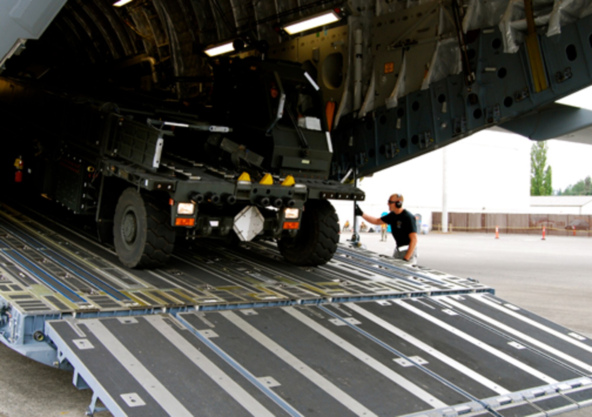Senior Airman Daniel Bryant, 436th Aerial Port Squadron, gives an all clear signal to Senior Airman Jonas Powers, 436th APS, as he drives a loader down the ramp of Team Dover's C-17 Globemaster III during a graded exercise July 23. Aerial porters from the 512th and 436th Airlift Wings teamed together in the 2009 Air Mobility Command RODEO at McChord Air Force Base, Wash., where they met several challenges aimed at testing their operational skills. (U.S. Air Force photo/Staff Sgt. Steve Lewis)