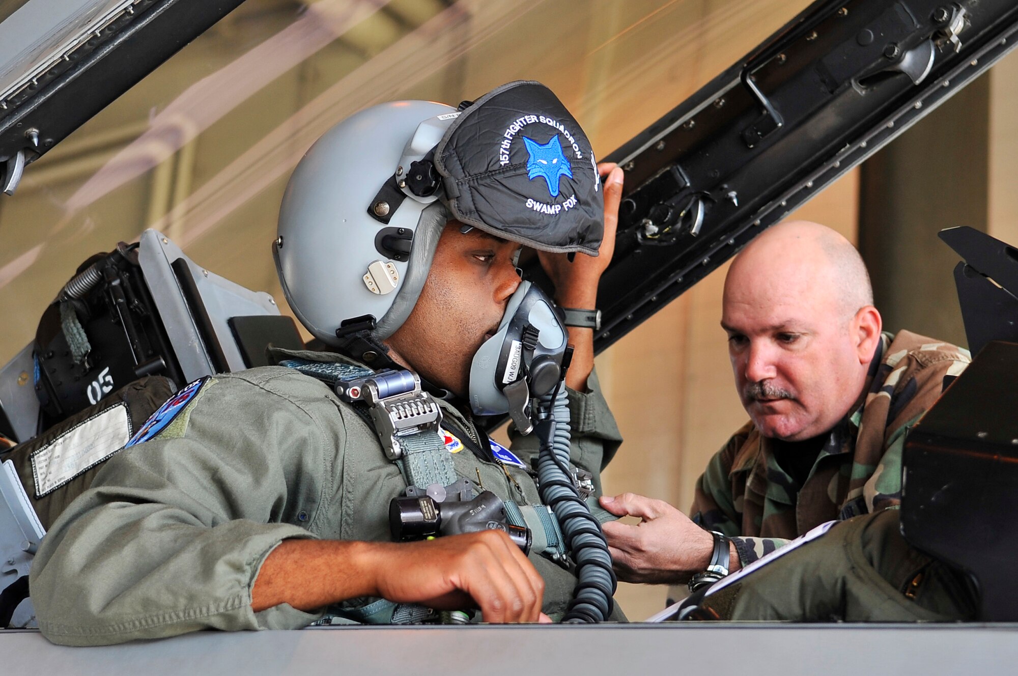 Capt. Taj Troy gets strapped in to his F-16 by Tech. Sgt. Michael Bilberry while taxing to the runway during Red Flag-Alaska 09-3 July 24, 2009, Eielson Air Force Base. RF-A provides unique opportunities to integrate various forces into joint, coalition and bilateral training from a simulated forward operating base. Captain Troy is an F-16 pilot and Sergeant Bilberry is an F-16 crew chief. Both are assigned to the 169th Fighter Wing, South Carolina Air National Guard. (U.S. Air Force photo/Staff Sgt. Christopher Boitz) 