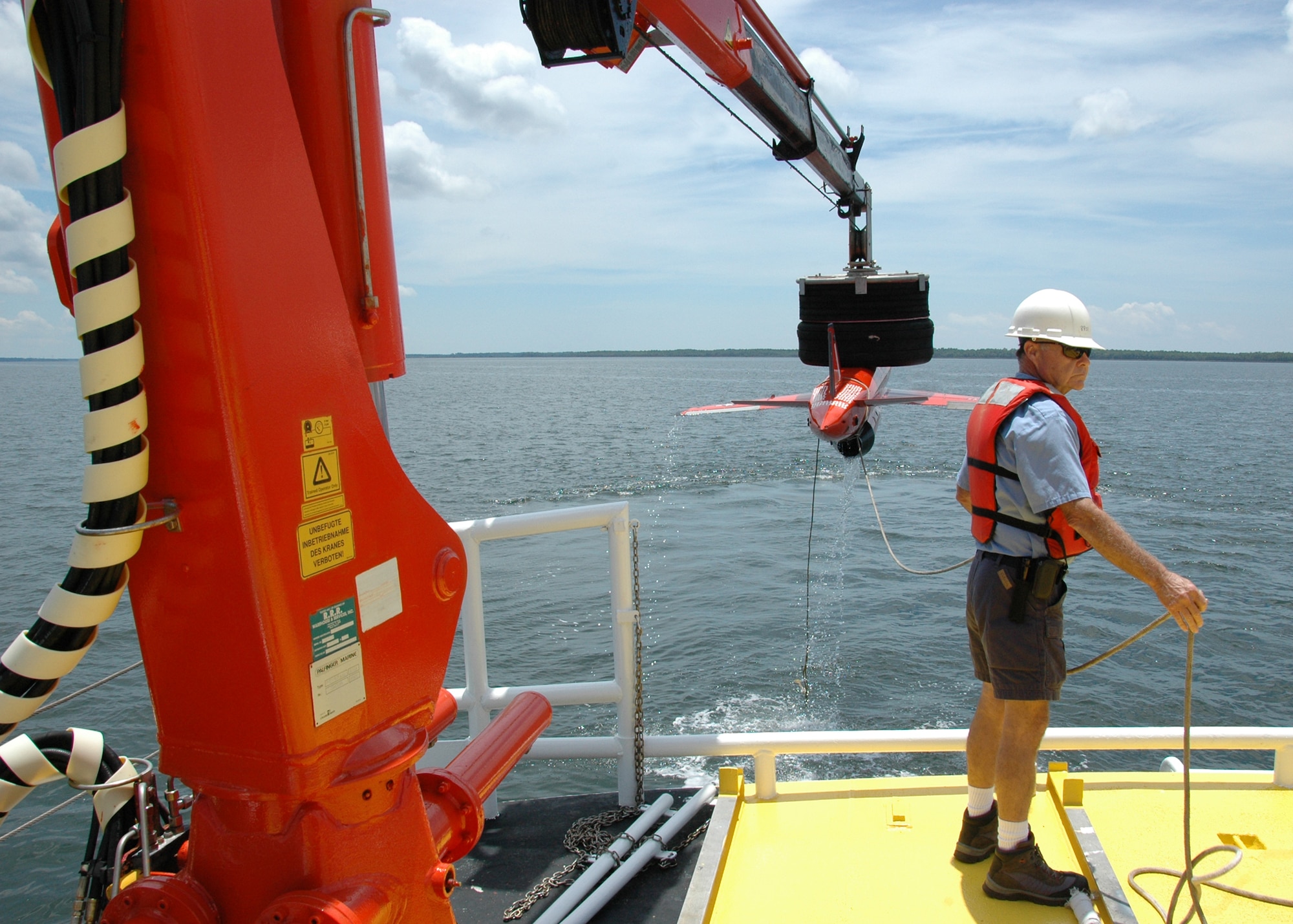Byron Howle directs the crane movements to pick up the model BQM-167 sub-scale drone during a recovery demonstration July 22 in the waters off of Tyndall Air Force Base, Fla. The ship used for recovery is one of only three 120-foot boats owned by the Air Force. They are contracted from Florida Offshore through the 82nd Aerial Targets Squadron to help recover sub-scale drones after they are shot down during live fire exercises conducted by the 53rd Weapons Evaluation Group. (U.S. Air Force photo/Samuel King Jr.)