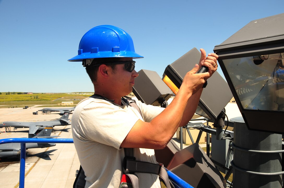 Staff Sgt. James Livingston, 28th Civil Engineer Squadron electrical systems craftsman, unscrews a light cover before removing the light ballasts here, July 22.  Sergeant Livingston checks the light bulbs as well as the ballast, which acts as an individual transformer for each light fixture.  The light fixtures serve as extra security at night on the flightline. (U.S. Air Force photo/Airman 1st Class Anthony Sanchelli)