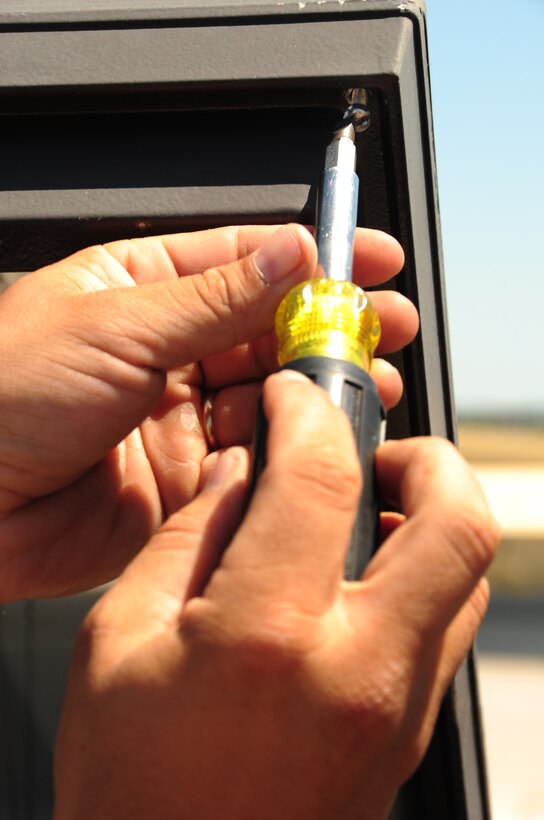 Staff Sgt. James Livingston, 28th Civil Engineer Squadron electrical systems craftsman, unscrews a light cover before removing the light ballasts here, July 22.  Sergeant Livingston checks the light bulbs as well as the ballast, which acts as an individual transformer for each light fixture.  The light fixtures serve as extra security at night on the flightline. (U.S. Air Force photo/Airman 1st Class Anthony Sanchelli)