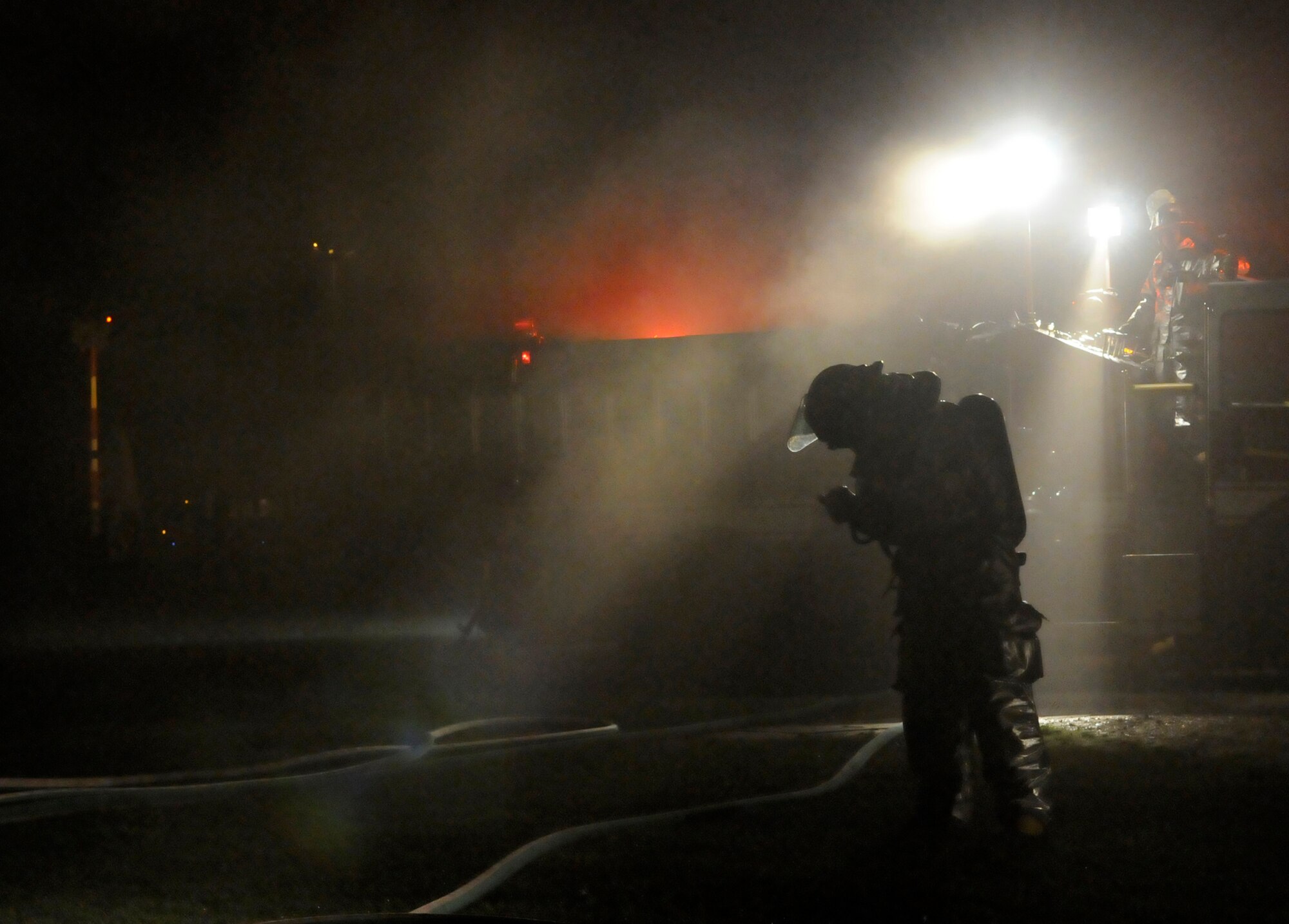 RAF MILDENHALL, England – A lone firefighter checks his equipment in a haze of smoke from a simulated building fire during an operational readiness exercise July 23.  The exercise is designed to prepare Airmen to do their jobs in a deployed environment and in a worst-case scenario.  (U.S. Air Force photo by Staff Sgt. Christopher L. Ingersoll)