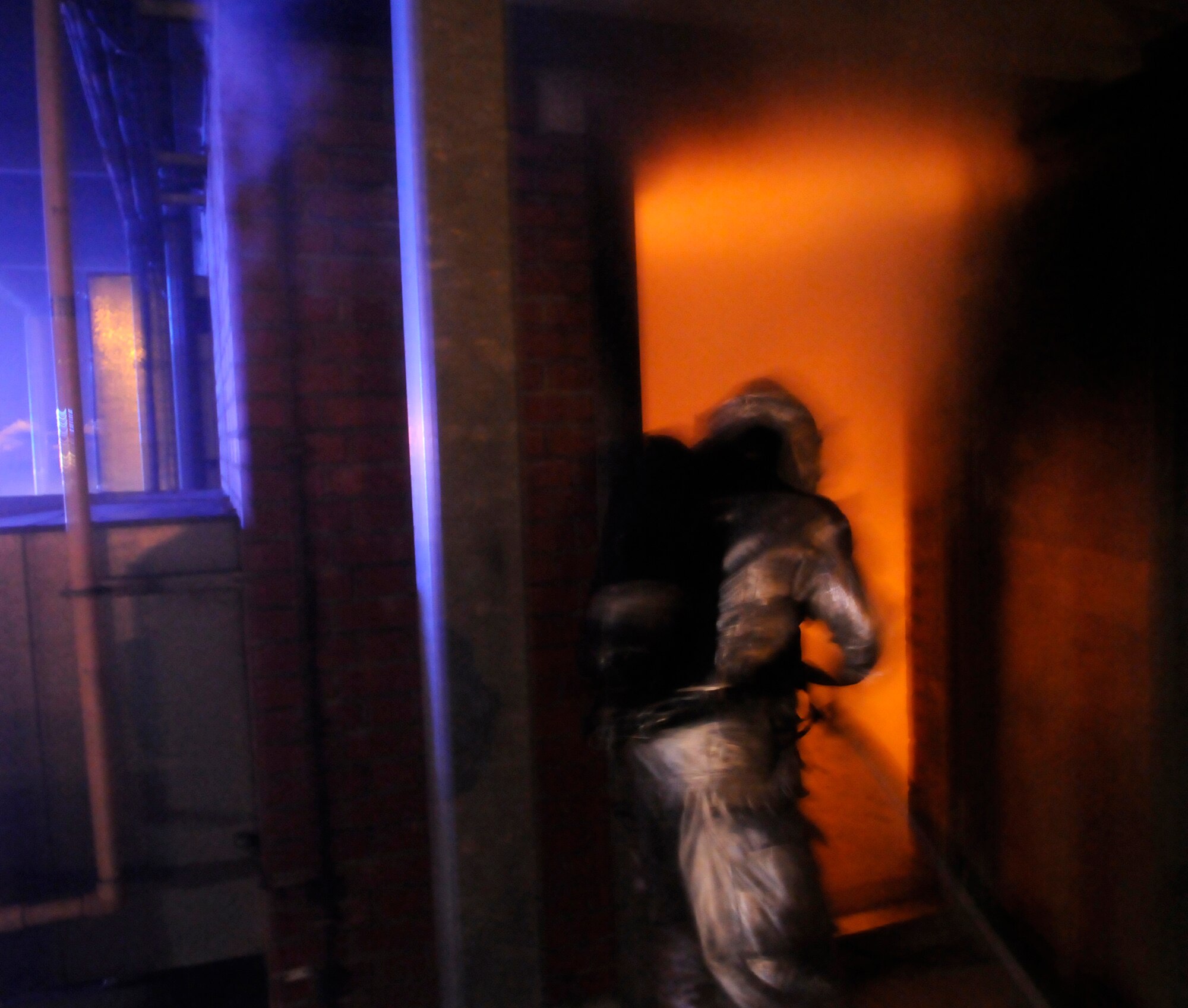 RAF MILDENHALL, England – A firefighter feeds a hose into a blazing hot room filled with smoke where two of his comrades have rushed to quell the flames and look for casualties as part of the phase-two operational readiness exercise July 23.  The fire department is inspected by noncommissioned officers to ensure everything is done safely and efficiently.  (U.S. Air Force photo by Staff Sgt. Christopher L. Ingersoll)