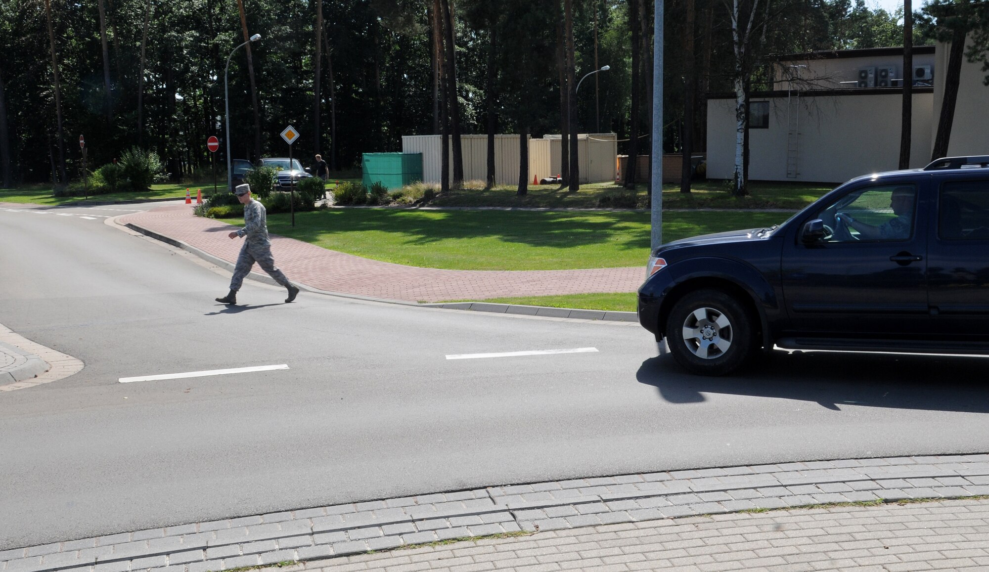 U.S. Air Force Airman 1st Class Caleb Pierce, 86th Airlift Wing Public Affairs photographer, crosses the street while a vehicle yields for him at Ramstein Air Base, Germany, July 22, 2009. In Germany, pedestrians have the right-of-way while vehicles exit the traffic circle, but vehicles have the right-of-way upon entry to the circle. (U.S. Air Force photo by Airman 1st Class Grovert Fuentes-Contreras)