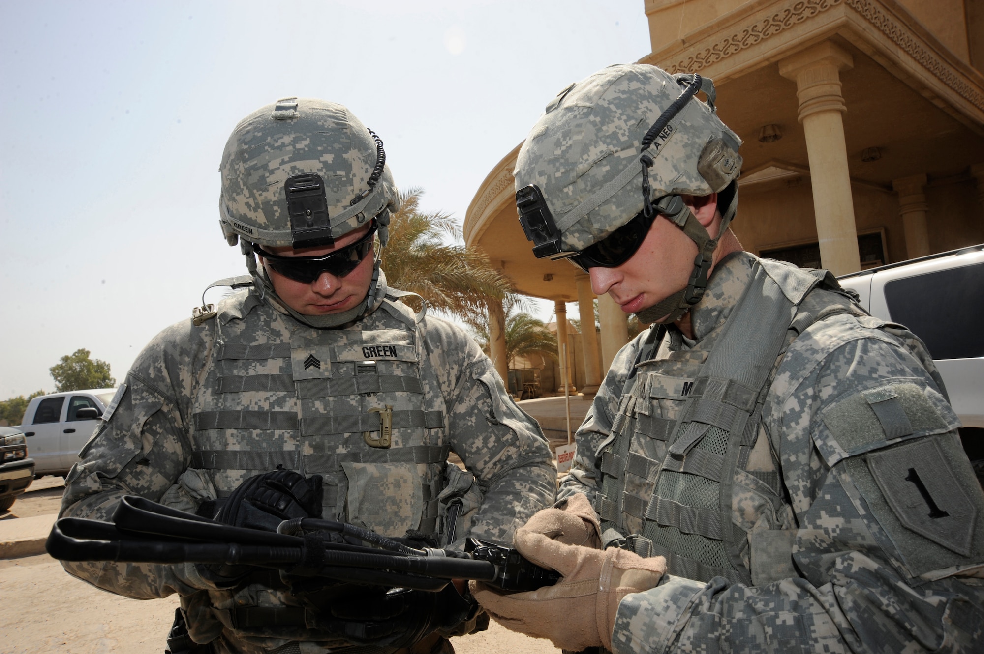 BAGHDAD, Iraq - Prior to the start of a mission, Army Sgt. Justin Green (left) and Pfc. Michael Moore (right) program a simple key loader to allow their radios to communicate securely between vehicles during a detail here July 20, 2009. Their personal security detail team provides constant security to the individual they are assigned to ensure the member is safely and securely transported to, from and inside various locations. Sergeant Green is originally from Madison, W.Va., and Private Moore is from Memphis, Tenn. Both are deployed from the 2nd Brigade Heavy Combat Team, 1st Infantry Division, Fort Riley, Kan. (U.S. Air Force photo/Tech. Sgt. Johnny L. Saldivar/Released)