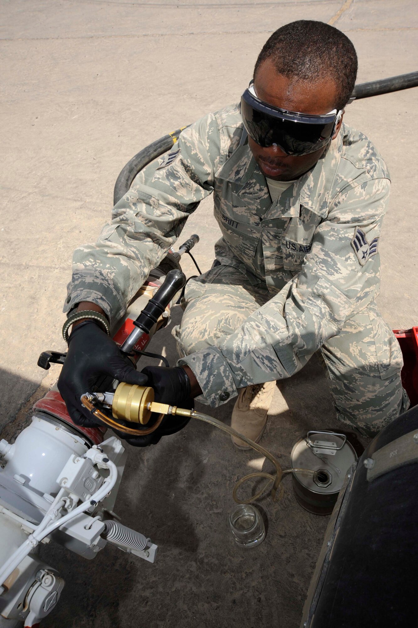 SATHER AIR BASE, Iraq -- Senior Airman David Britt, 447th Expeditionary Logistics Readiness Squadron fuels lab technician, connects an in-line sampler to a connection device here July 20, 2009.  Airman Britt primarily built the apparatus, nicknamed "Frankenstein," which re-circulates fuel through the hose to the apparatus, allowing him to safely retrieve samples to test the fuel for water and sediment. Airman Britt is deployed from McConnell Air Force Base, Kan., and is a native of Enterprise, Ala.  (U.S. Air Force photo/Tech. Sgt. Johnny L. Saldivar/Released)