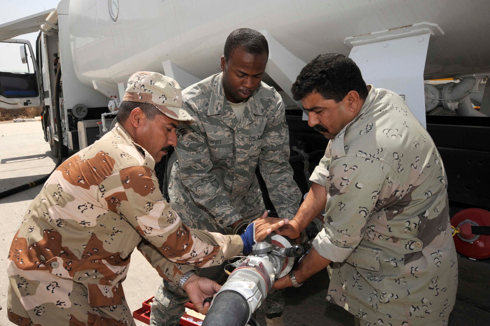 SATHER AIR BASE, Iraq -- Senior Airman David Britt, 447th Expeditionary Logistics Readiness Squadron fuels lab technician, and Iraqi air force members connect "Frankenstein" to an Iraqi fuel truck here July 20, 2009. "Frankenstein" is a fuel sampling connection built primarily by Airman Britt to re-circulate fuel through the hose to the apparatus allowing an individual to safely retrieve a fuel sample. Samples are taken weekly and tested for water and sediment to ensure the Iraqi air force receives the highest quality fuel possible. Airman Britt is deployed from McConnell Air Force Base, Kan. and is a native of Enterprise, Ala.  (U.S. Air Force photo/Tech. Sgt. Johnny L. Saldivar/Released)