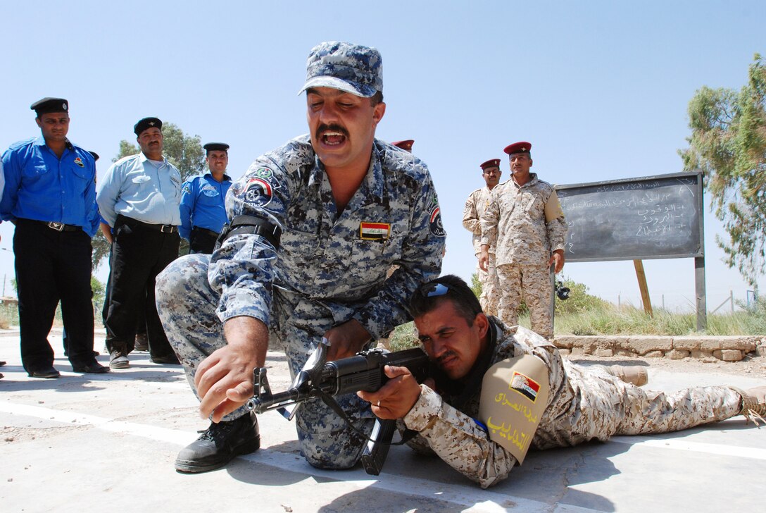 Capt. Hayder Adnan Ali, Iraqi police liaison to coalition forces, explains what happens when an AK-47 rifle round fires as Sgt. Hayder Sahib Silan, Iraqi police mobile training team instructor, demonstrates at the Iraqi police provincial headquarters in Wasit, Iraq, July 20, 2009. U.S. Army photo by Sgt. 1st Class Joe Thompson