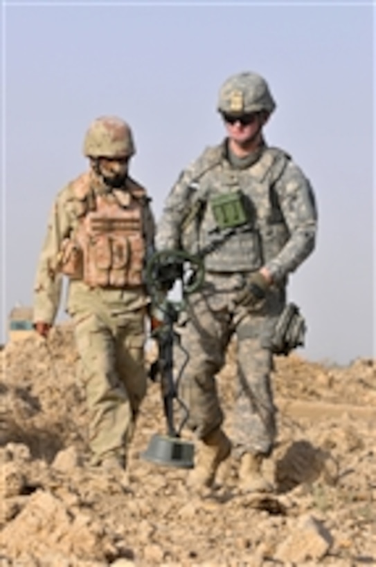 A U.S. Army soldier with 1st Platoon, Comanche Troop, 1st Squadron, 150th Cavalry Regiment, 30th Heavy Brigade Combat Team, 1st Cavalry Division helps Iraqi soldiers with 1st Company, 3rd Battalion, 23rd Brigade, 17th Iraqi Division conduct weapons cache searches through open fields in the Radwaniyah area outside Baghdad, Iraq, on July 18, 2009.  