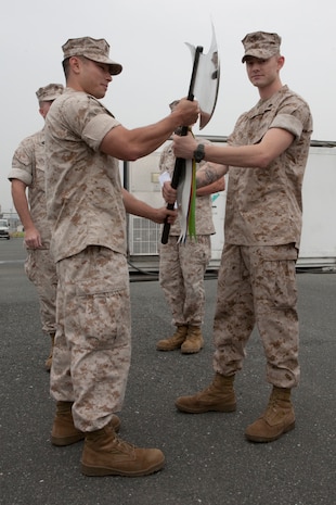 Cpl. Morgan Yocum, a Marine Aviation Logistics Squadron 12 J52 jet engine mechanic, passes off the AIRSpeed division time to reliably replenish Battle-axe to Sgt. Michael Uribe, a MALS-12 electronic counter measures technician here July 24. The Battle-axe represents outstanding TTR improvement by one of 42 maintenance work centers.