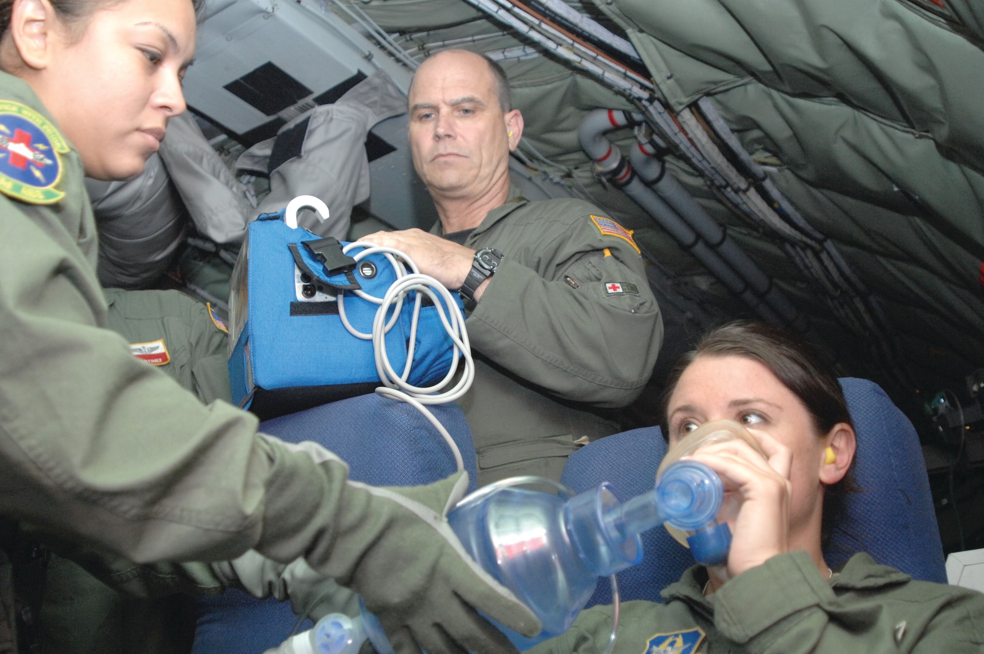 Bush Field, Ga. U.S. Air Force Tech. Sgt. Lisa Perales, left, a medical technician with the 433rd Aeromedical Evacuation Squadron, Lackland AFB, Texas, and MSgt James Cooke, center, head charge nurse with the 914th Air Wing, Niagara Falls, N.Y., administer medical treatment to SSgt Ashley Finaro, right, also a med tech with the 914th, for a simulated hypoxia patient scenario during aeromedical evacuation training on a KC-135R aircraft on June 14. (U.S. Air Force photo/ Senior Master Sgt. Kim Allain)