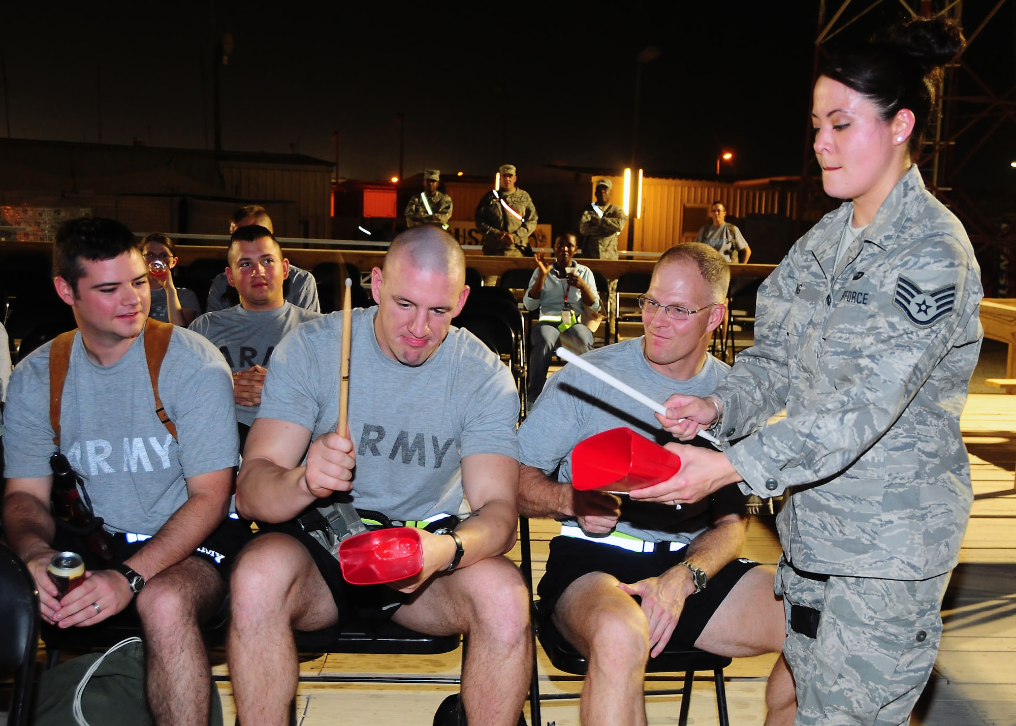 CAMP BUCCA, Iraq-- Staff Sgt. Angie Long, Air Force Central Command Sonora band, shows members of Camp Bucca, Iraq, how to keep the beat with a cow bell during a performance on July 22.  Sonora offers a diverse performance repertoire featuring acoustic, electric and bass guitars, keyboards, drums, saxophone and trumpet.  Vocalists round-out the mix and an expert engineer brings it all together.  Sergeant Long is deployed from the 131st Fighter Wing, Air National Guard, Mo., and hails from Nashville, Tenn.  (U.S. Air Force photo/Tech Sgt. Tony Tolley)