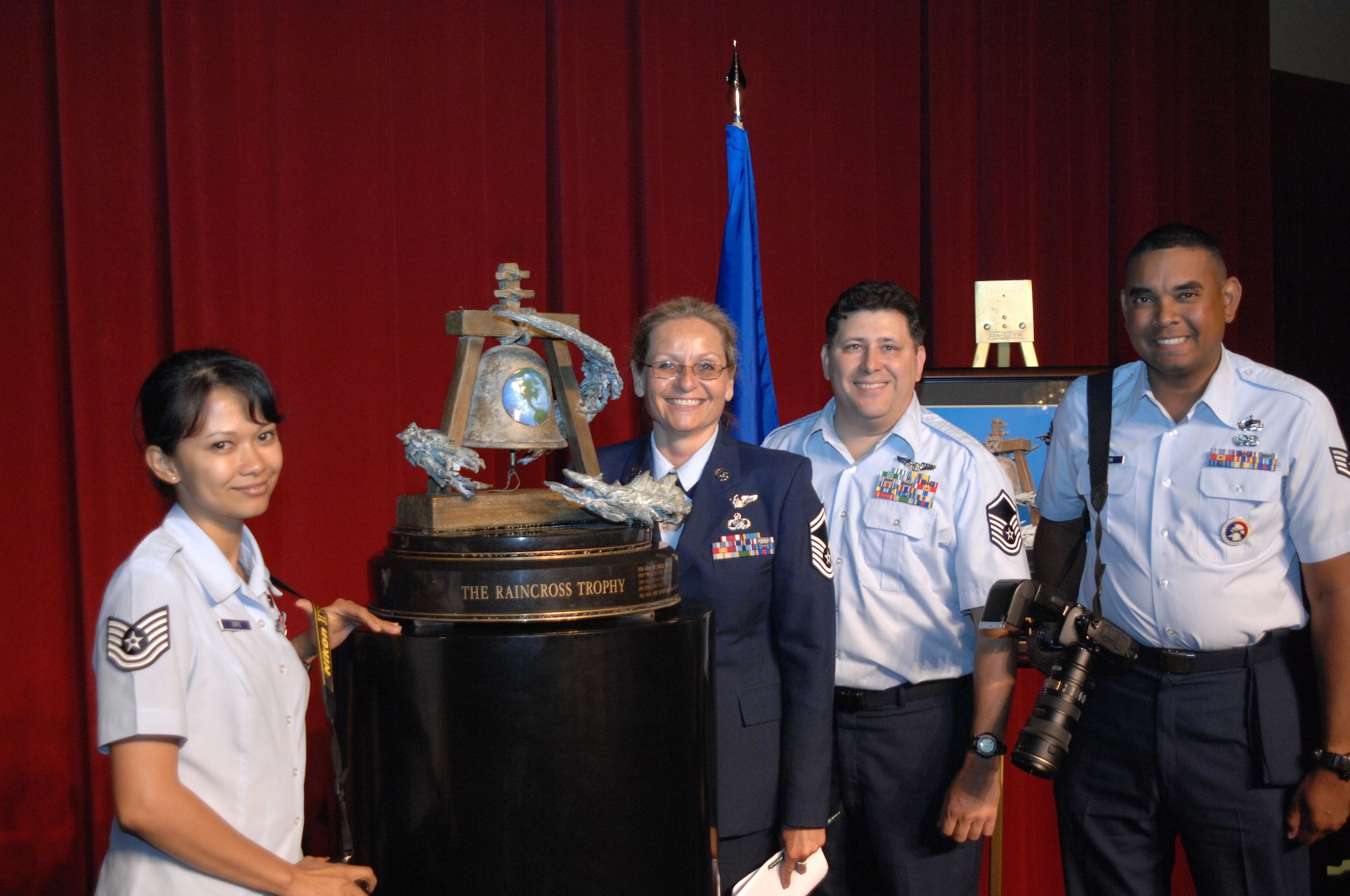 From left to right, Technical Sgt. Carolyn Erfe, Senior Mater Sgt. Kim Allain, Master Sgt. Roy Santana, and Technical Sgt. Keith Lawson, photographers with the 4th Combat Camera Squadron, March Air Reserve Base, Calif., pose with the Raincross Trophy after it was awarded to the 452nd Air Mobility Wing, March ARB, Calif, at the 11th Annual Raincross Trophy Dinner held July 23, 2009, at the Riverside Convention Center, Riverside, CA. Fourth Combat Camera is slated to administratively realign under the March wing in the near future.  (U. S. Air Force photo/ Senior Master Sgt. Kim Allain)  (released)