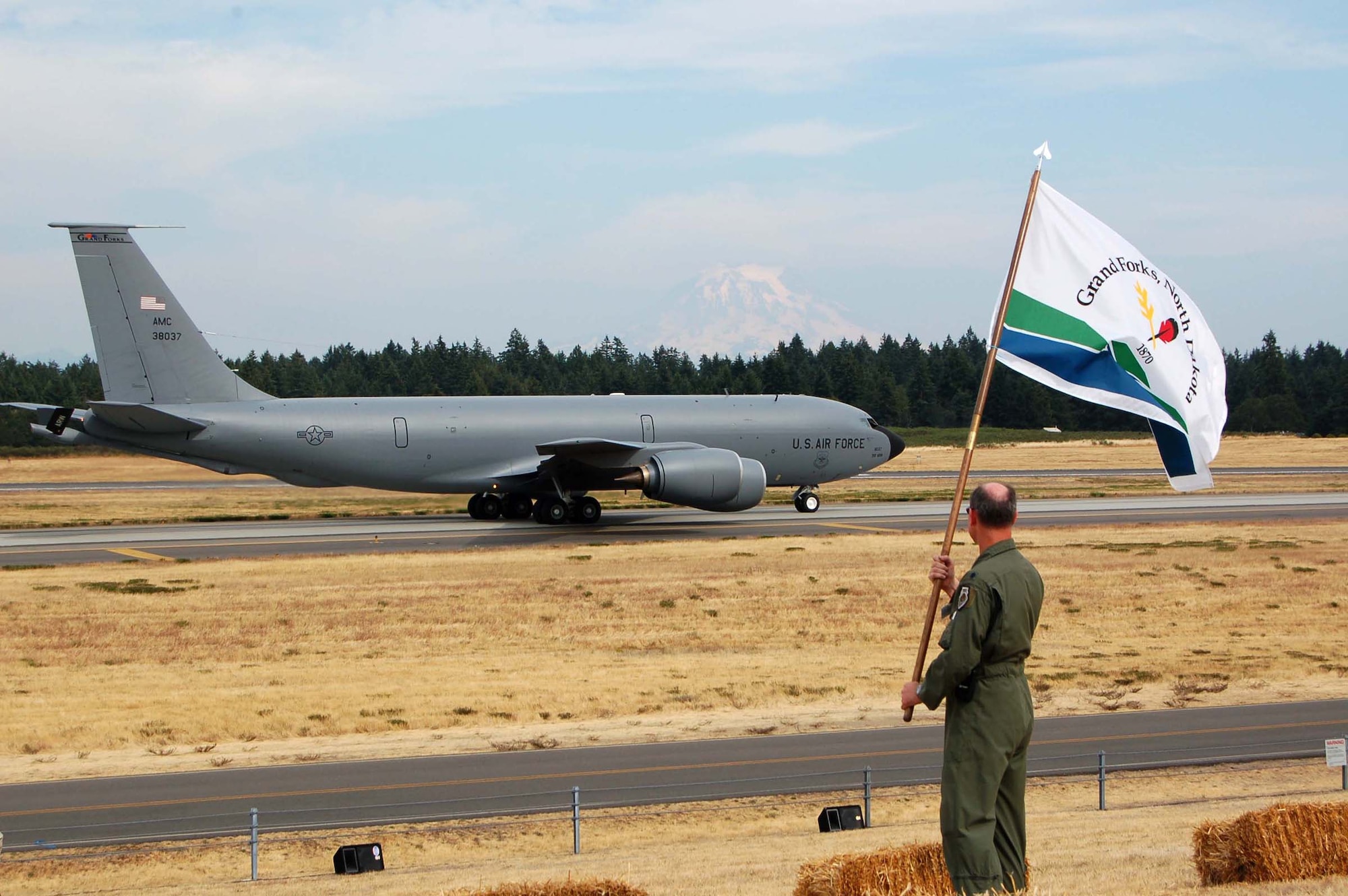 A Grand Forks Air Force Base KC-135 taxis in preparation to take flight as team lead, Lt. Col. Seth Beaubien, waves the Grand Forks flag proudly at McChord AFB, Wash., July 21 during the Air Mobility RODEO competition. RODEO is an international combat skills and flying operations competition designed to develop and improve techniques and procedures that enhance air mobility operations and to promote esprit de corps, optimizing mobility partnerships.  (U.S. Air Force photo/Tech. Sgt. Amanda Callahan)