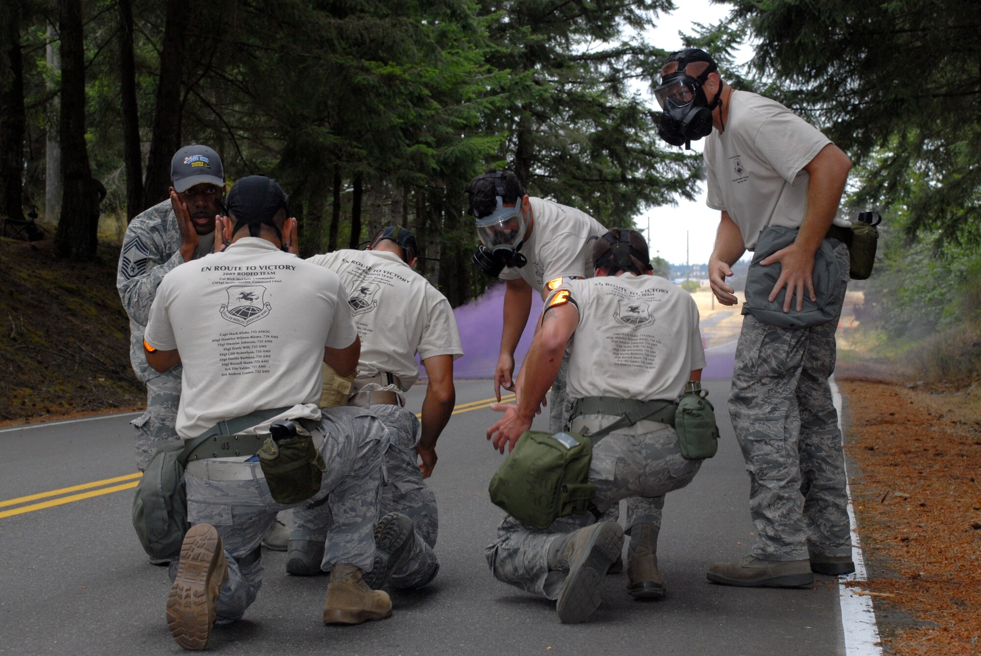 MCCHORD AIR FORCE BASE, Wash. – The 515th Air Mobility Operations Wing Air Mobility Rodeo 2009 Pacific aerial porters Senior Airman Tito Valdez, 731st Air Mobility Squadron, Osan Air Base, Korea; Senior Airman Andrew Cramer, 732th Air Mobility Squadron, Elmendorf Air Force Base, Alaska; Staff Sgt. Dustin Barboza, 734th Air Mobility Squadron, Andersen Air Base, Guam; Staff Sgt. Clifton Robertson, 735th Air Mobility Squadron, Hickam Air Force Base, Hawaii; and Staff Sgt. Travis Wilt, 733rd Air Mobility Squadron, Kadena Air Base, Japan, don gas masks during the Aerial Porters Combat Challenge here July 23. During the challenge, aerial porters had to sprint along a four-mile course, stopping to overcome physical and mental obstacles. After they encountered this purple-smoked improvised explosive device, they ran in gas masks approximately a quarter mile to the next challenge station. They finished the entire course in 57 minutes and 26 seconds. (U.S. Air Force photo/Staff Sgt. Carolyn Viss)