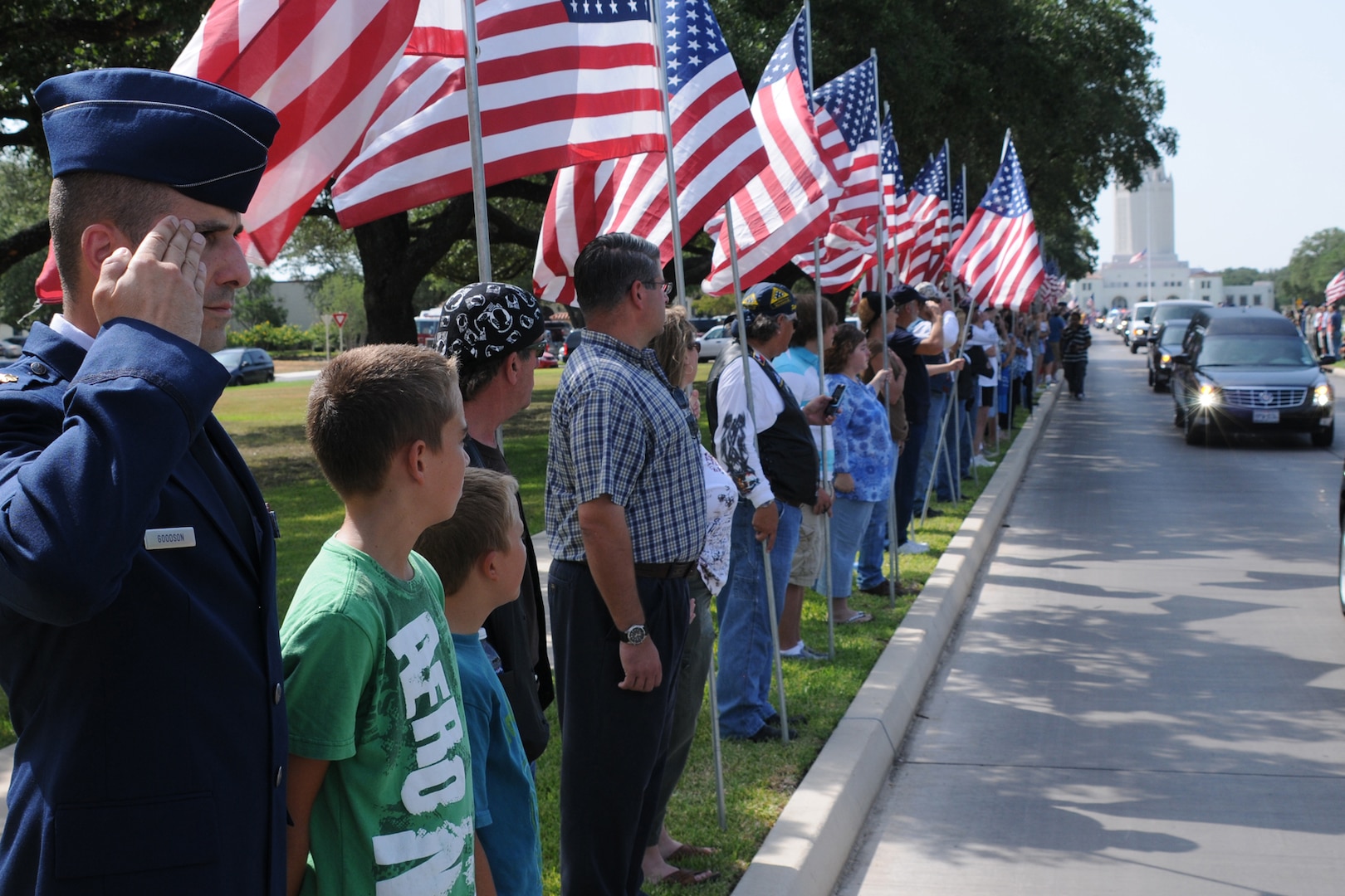 Maj. J.T. Goodson salutes the motorcade carrying the
casket of Marine Corps Lance Cpl. Brandon Lara as his sons Hunter (second
from left) and Logan watch the vehicles make their way down Harmon Drive at
Randolph Air Force Base July 26. (U.S. Air Force photo/Don Lindsey)