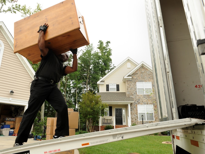 LANGLEY AIR FORCE BASE, Va. – Eric Andrews, warehouse worker/packer, carries  a cabinet to the moving truck July 23. Summer season is one of the busiest times for a Permanent Change-of-Station for military members. One important rule to preparing for PCS is organization. (U.S. Air Force photo/Airman 1st Class Gul Crockett)