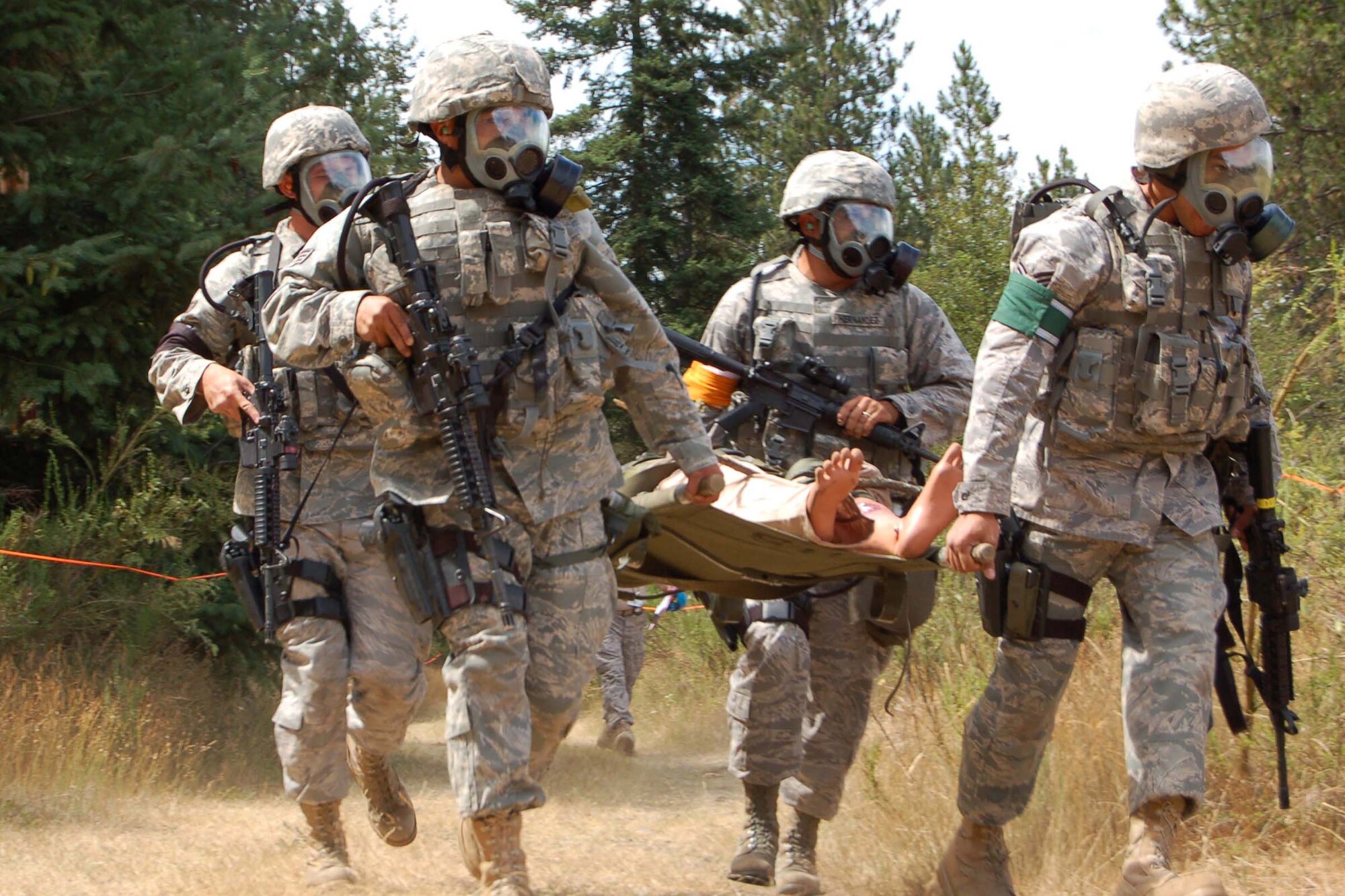 319th Air Refueling Wing security forces defenders perform a litter carry after donning gas masks during the combat weapons course at the Air Mobility RODEO July 20. (U.S. Air Force photo/Tech. Sgt. Amanda Callahan)