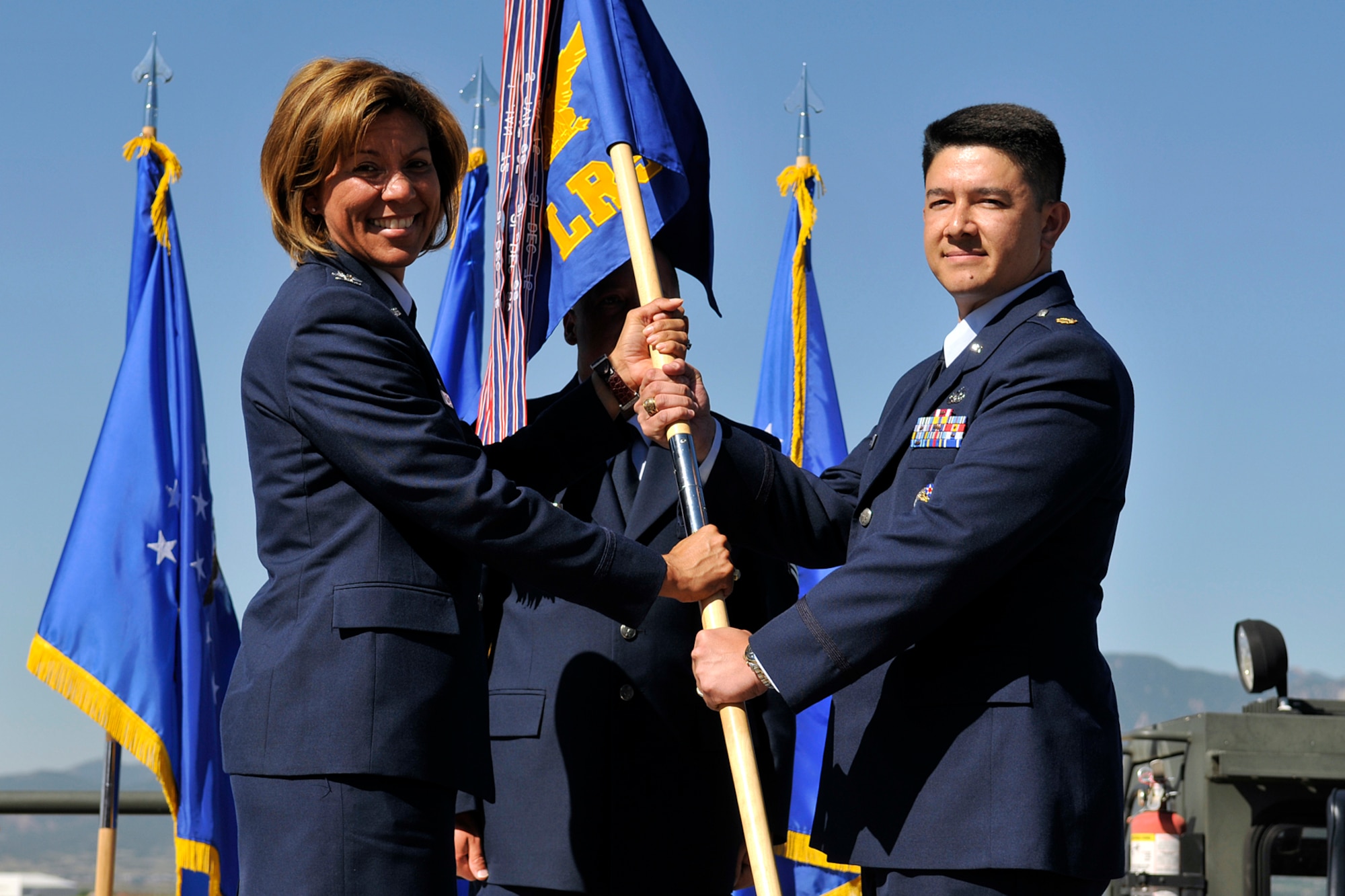 PETERSON AIR FORCE BASE, Colo. -- Col. Emily Buckman, 21st Mission Support Group commander, passes the 21st Logistic Readiness Squadron guidon to Maj. Jerry Gonzalez during the LRS change of command ceremony July 14. Major Gonzalez’s previous assignment was as the logistics readiness office functional manager at the Pentagon. Lt. Col James Smith, previous 21st LRS commander, retired but remains in the local area. (Air Force photo by Larry Hulst)  