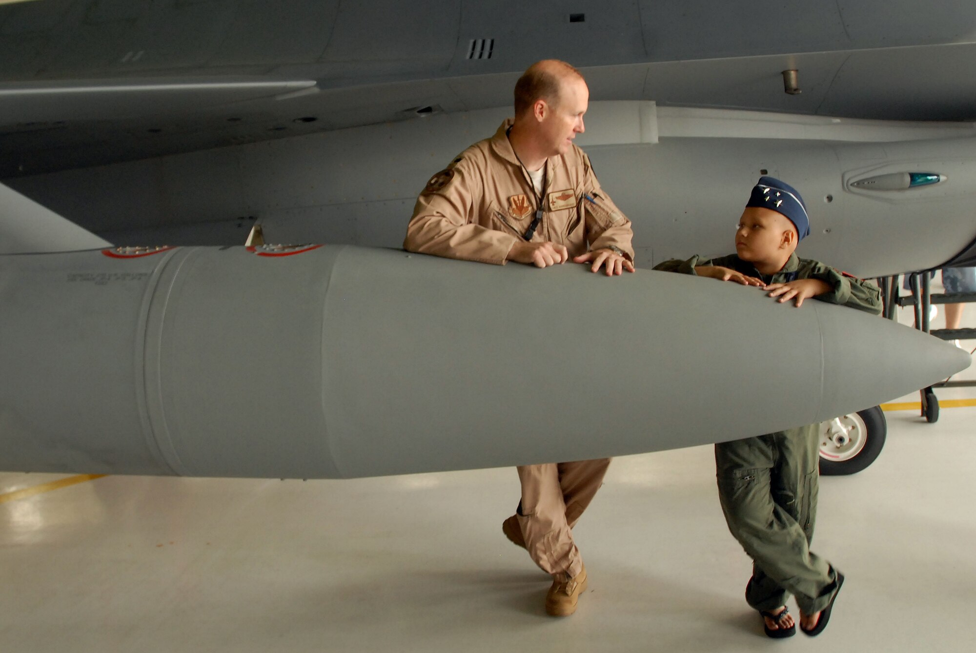 Air Force Lt. Col. Chris Hardgrave, left, an F-16 Fighting Falcon pilot with
the 121st Fighter Squadron, talks with Kayla Kiley who was visiting the
squadron as part of the Pilot for a Day program at Andrews Air Force Base,
Md., Thursday, July 23, 2009. The Pilot for a Day program, which started at
the base in 2004, allows children with serious or life-threatening illnesses
and their families to meet and interact with personnel from a variety of
units at the base and get hands-on demonstrations of the aircraft and
equipment those units use.  
