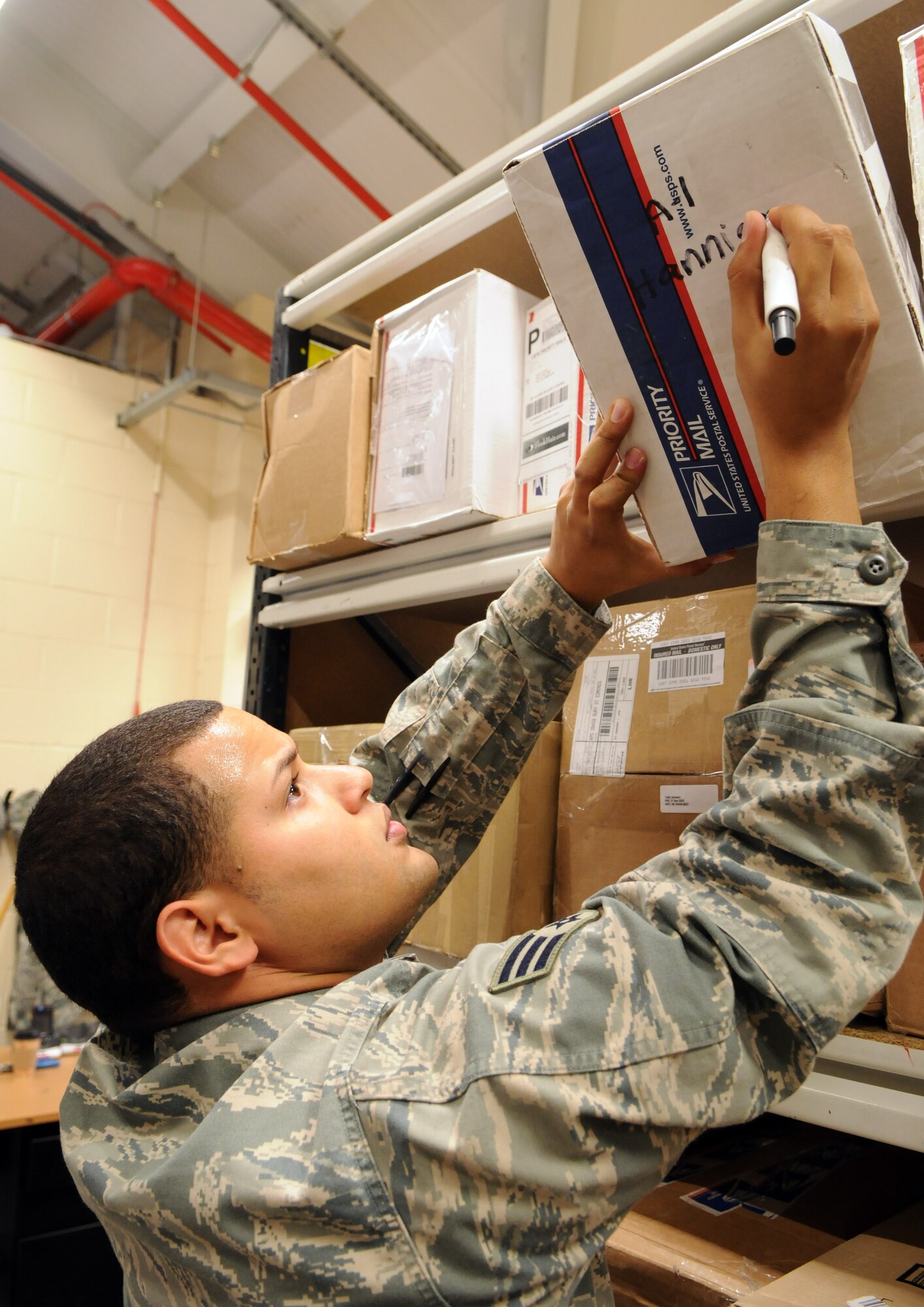 RAF MILDENHALL, England -- Senior Airman Victor Salas-Pellot, RAF Mildenhall post office, annotates name and location on a newly arrived package.  When the customer shows up to retrieve the box, they have a slip of paper telling the postal clerk what shelf the box is on, making the whole system quick and efficient.  (U.S. Air Force photo by Staff Sgt. Austin M. May)
