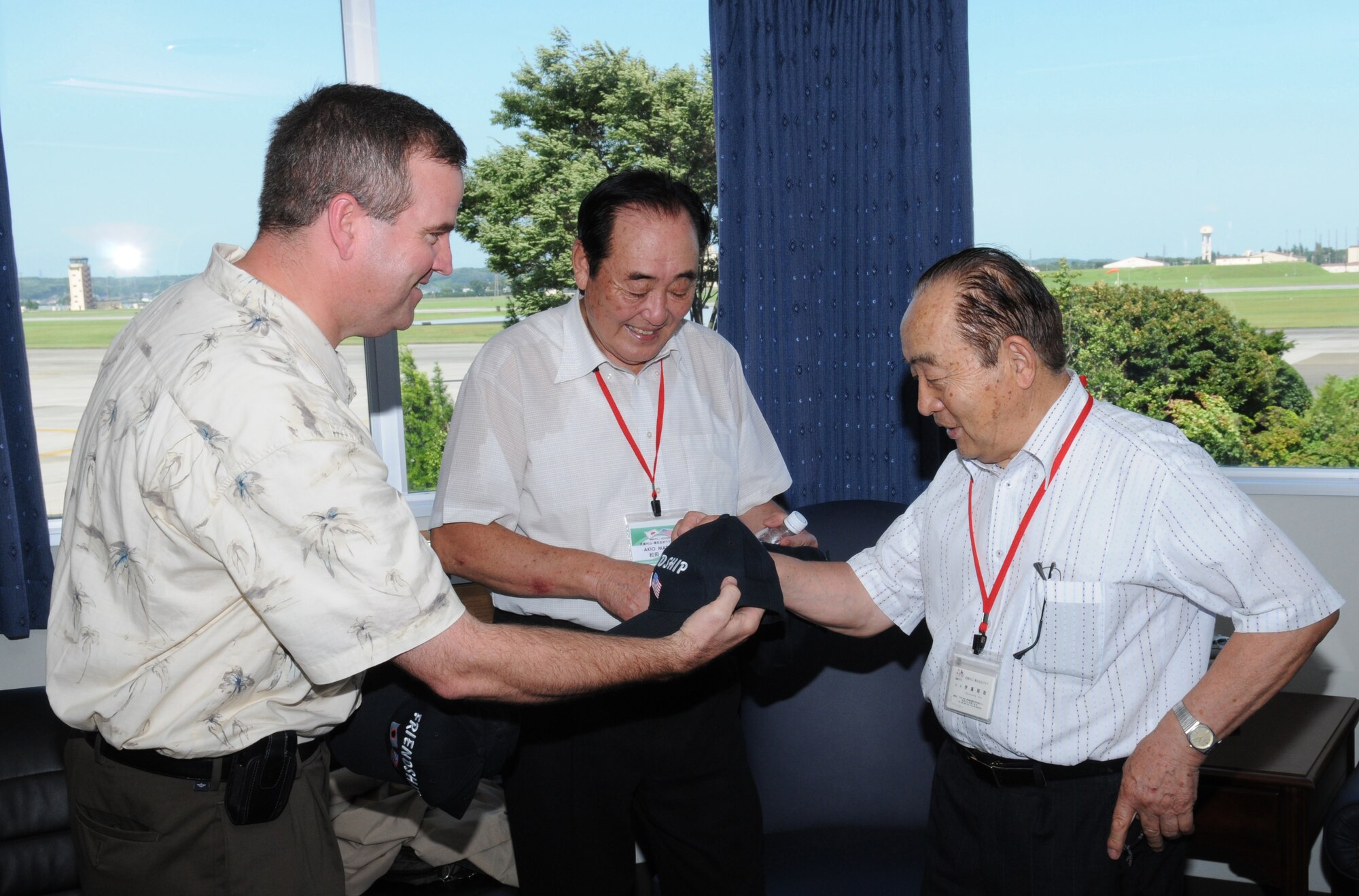 YOKOTA AIR BASE, Japan -- (From left to right) Colonel Mark Hering, 374th Operations Group commander, presents friendship hats to Akio Matsuda, advisor to the Musashimurayama Yokota Friendship Club, and Shosuke Ito, the club president, during a base tour July 26. The operations group marked the club's second anniversary by conducting a base tour and planting a tree near the Yujo Community Center as a symbol of friendship between the citizens of Musashimurayama and the group. (U.S. Air Force photo/Airman 1st Class Sean Martin)