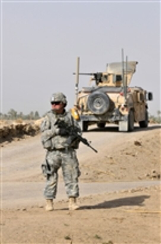 A U.S. Army soldier with 1st Platoon, Comanche Troop, 1st Squadron, 150th Cavalry Regiment, 30th Heavy Brigade Combat Team, 1st Cavalry Division provides security as Iraqi soldiers with 1st Company, 3rd Battalion, 23rd Brigade, 17th Iraqi Division conduct weapons cache searches through open fields in the Radwaniyah area outside Baghdad, Iraq, on July 18, 2009.        A U.S. Army soldier with 1st Platoon, Comanche Troop, 1st Squadron, 150th Cavalry Regiment, 30th Heavy Brigade Combat Team, 1st Cavalry Division provides security as Iraqi soldiers with 1st Company, 3rd Battalion, 23rd Brigade, 17th Iraqi Division conduct weapons cache searches through open fields in the Radwaniyah area outside Baghdad, Iraq, on July 18, 2009.  DoD photo by Petty Officer 2nd Class Edwin L. Wriston, U.S. Navy.  (Released)