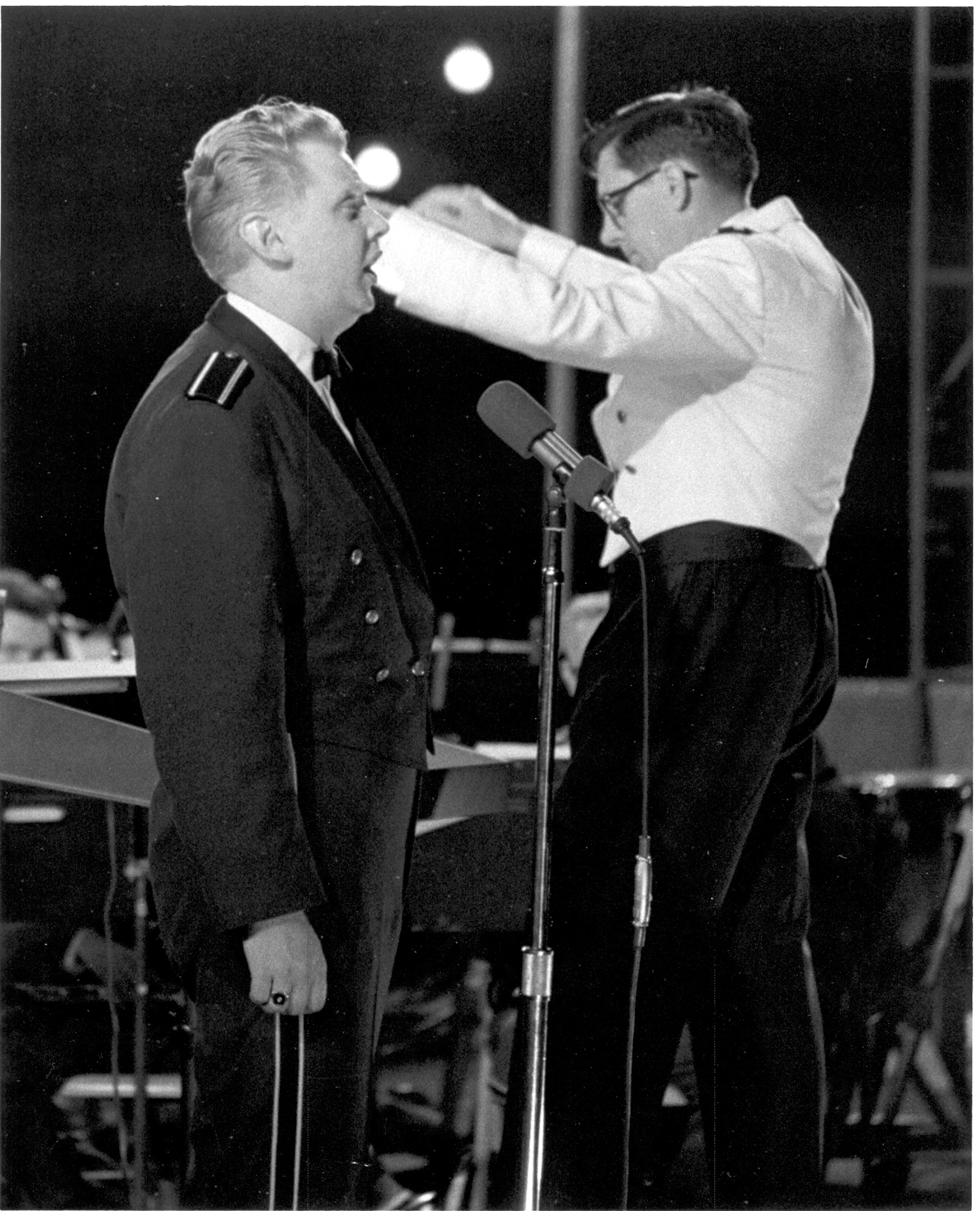 Vocalist Chuck Kuliga solos with The United States Air Force Band in an outdoor summer concert in 1968 or 1969 on the East side of the Capitol Building.  The conductor is Captain Albert A. Bader, assistant conductor to Lieutenant Colonel Arnald D. Gabriel, The Air Force Band's commander and conductor.  (Official photo of The Air Force Band.)