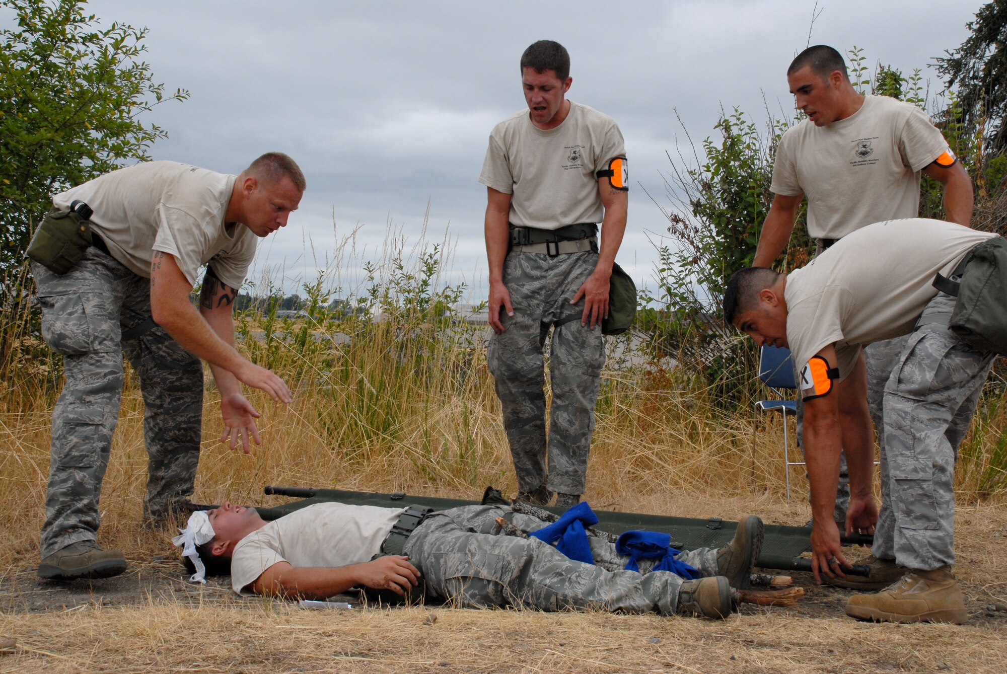 MCCHORD AIR FORCE BASE, Wash. – The 515th Air Mobility Operations Wing Air Mobility Rodeo 2009 Pacific aerial porters Staff Sgt. Travis Wilt, 733rd Air Mobility Squadron, Kadena Air Base, Japan; Staff Sgt. Clifton Robertson, 735th Air Mobility Squadron, Hickam Air Force Base, Hawaii; Senior Airman Andrew Cramer, 732th Air Mobility Squadron, Elmendorf Air Force Base, Alaska; and Senior Airman Tito Valdez, 731st Air Mobility Squadron, Osan Air Base, Korea; provide self aid and buddy care to “wounded” teammate Staff Sgt. Dustin Barboza, 734th Air Mobility Squadron, Andersen Air Base, Guam, during the Aerial Porters Combat Challenge here July 23. During the challenge, aerial porters had to sprint along a four-mile course, stopping to overcome physical and mental obstacles. They finished the entire course in 57 minutes and 26 seconds. The 515th AMOW team is an eight-person group of Airmen who were hand-picked from more than 500 other aerial porters in the Pacific to compete in the Rodeo 2009 competition July 19 to 25 here. Prior to the Rodeo, they trained together at Hickam Air Force Base, Hawaii, for seven weeks. (U.S. Air Force photo/Staff Sgt. Carolyn Viss)