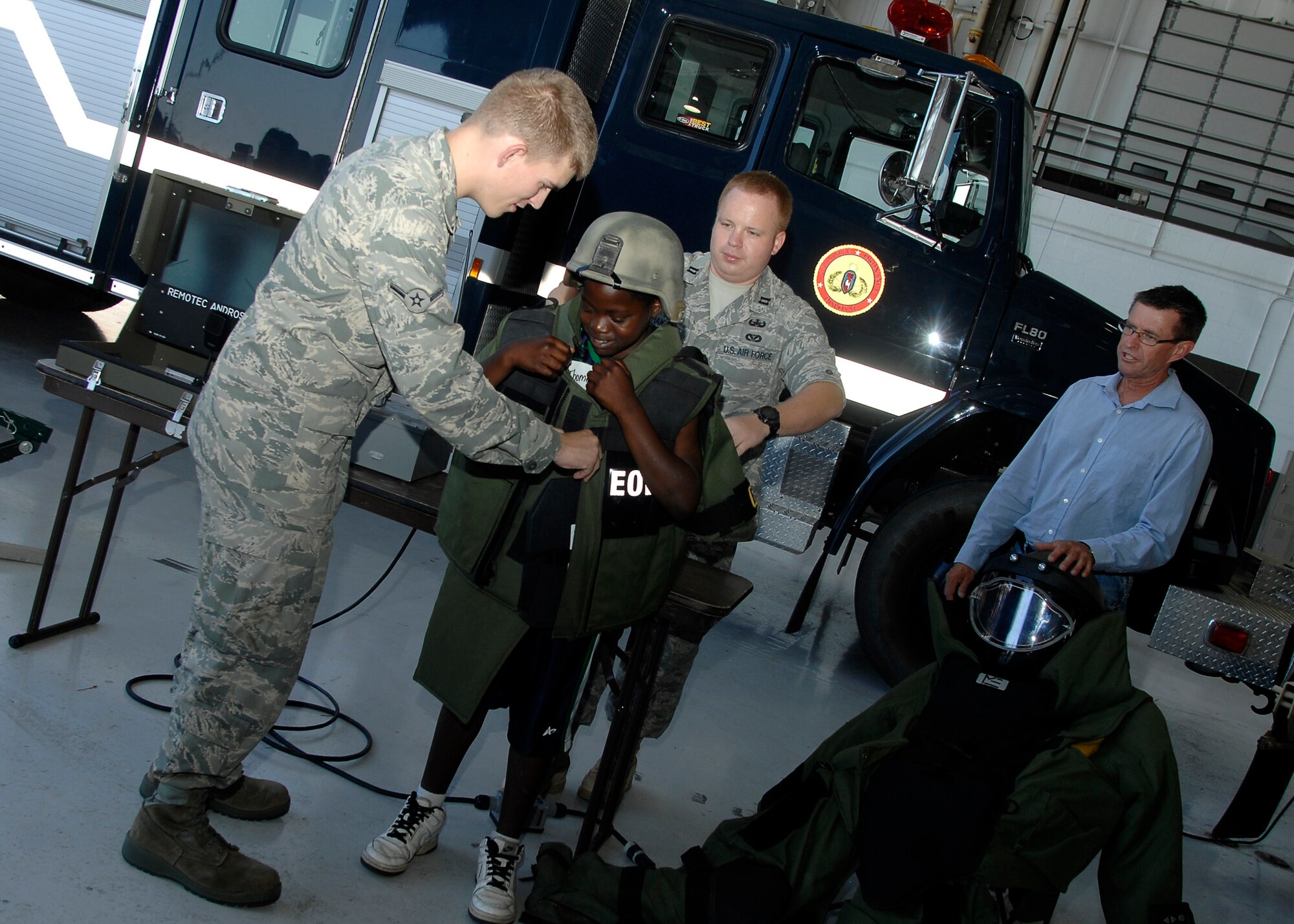 MCCONNELL AIR FORCE BASE, Kan. -- Capt. George Haka, 22nd Civil Engineer Squadron Explosive Ordnance Disposal officer, and Airman James Fuller, 22nd Maintenance Group help his “little,” Thomas, don bomb gear during the Big for a Day event at McConnell, July 24. Big for a Day is an annual Big Brothers/Big Sisters event at McConnell to teach children about different types of military careers. (Photo by Senior Airman Anthony Mejia)