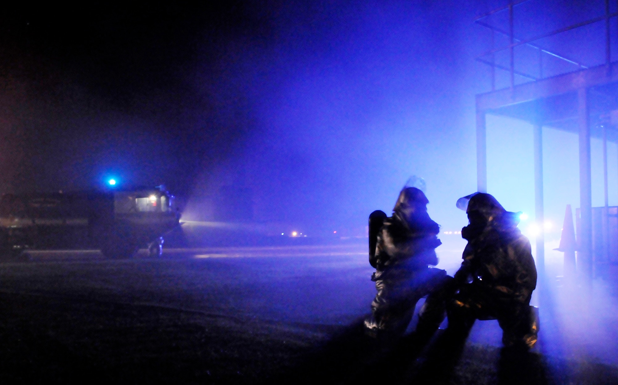 Two firefighters lean in close to shout out the plan of attack during a simulated building fire July 23 at Royal Air Force Mildenhall, England. The fire is one part of several days of training scenarios taking place during an operational readiness exercise. The firefighters are assigned to the 100th Civil Engineer Squadron. (U.S. Air Force photo/Staff Sgt. Christopher L. Ingersoll)