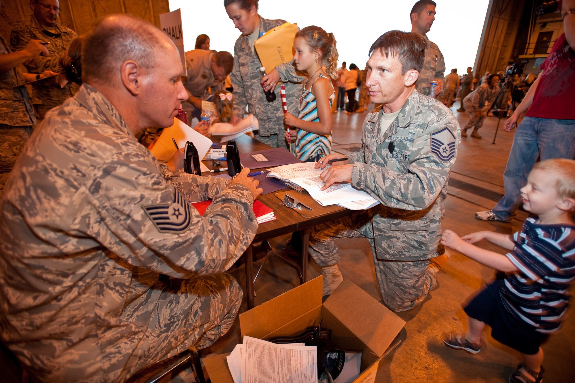 Air Force Master Sgt. JT Theiral is rushed by his son Jarret as he speaks with Tech. Sgt. Daniel Bruno, 140th financial management specialist, about his travel voucher. Master Sgt. Theiral is returning from a 90 day deployment to Joint Base Balad, Iraq. - (U.S. Air Force photo/Master Sgt. John Nimmo, Sr.) (RELEASED)