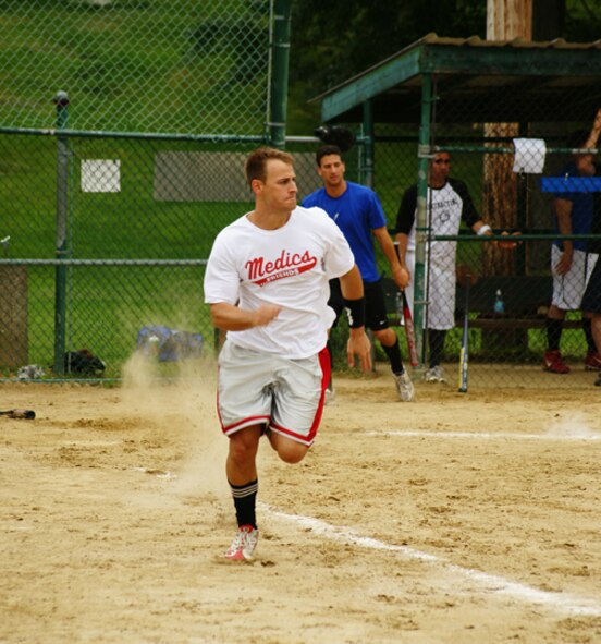 Capt. Mike Elliot, 66th Medical Operations Squadron, makes a run for first base as 2nd Lt. Frank Shiavone, 66th Contracting Squadron, prepares for his turn at bat  during a company grade officers vs. colonels and Top 3 softball game on July 15. (Courtesy photo by 1st Lt. Chris Wenz)