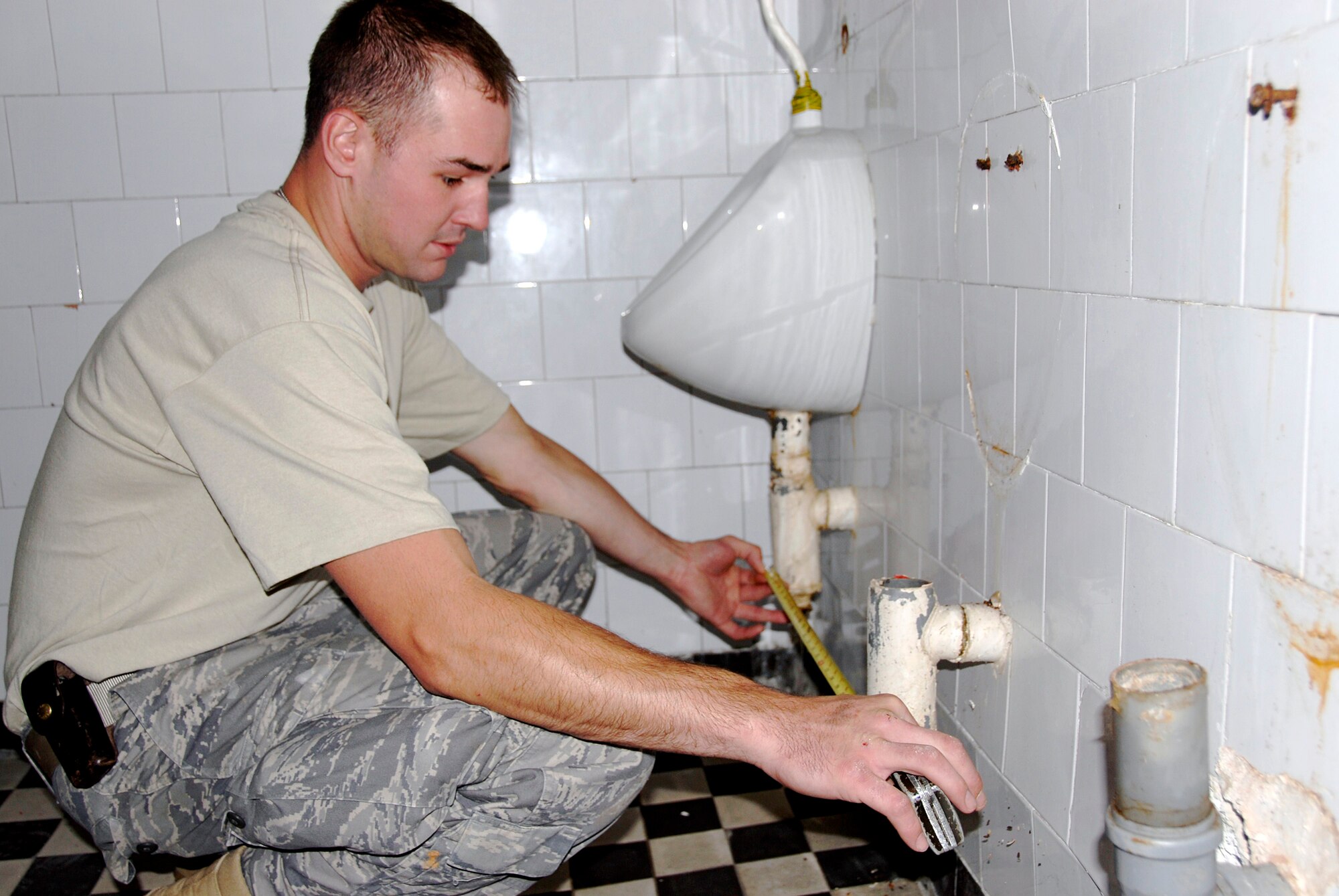 Staff Sgt. Doug Swigart, a plumber in the 133rd Airlift Wing?s Civil Engineering Squadron, obtains measurements in the bathroom of one of two buildings which the squadron is renovating on July 21, 2009. About forty Minnesota Airmen are in ?jd?r?gd, Hungary as part of their two week Deployment for Training. USAF photo by Staff Sgt. Amber Monio.