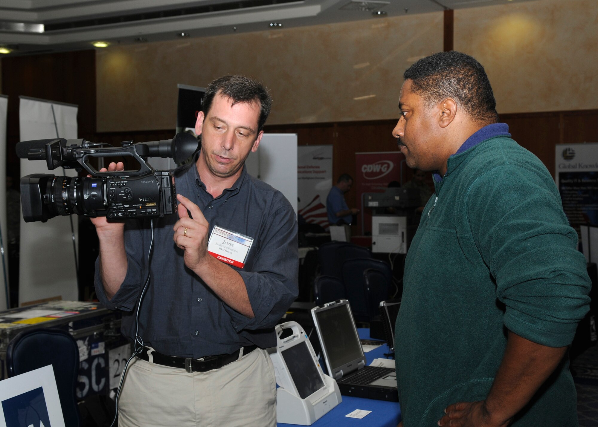 SPANGDAHLEM AIR BASE, Germany – James MacFadden, B&H Photo, Video, Pro Audio and Digital Imaging store representative, explains a Sony 3CMOS camcorder to Leonard Shanks, 52nd Logistics Readiness Squadron contractor, during the Spangdahlem Air Base Technology Exposition at Club Eifel July 24. The exposition was hosted by the Eifel Air Force Communications and Electronics Association and the 52nd Communications Squadron. There were more than 40 companies showcasing the latest technologies. (U.S. Air Force photo by Airman 1st Class Staci Miller) 