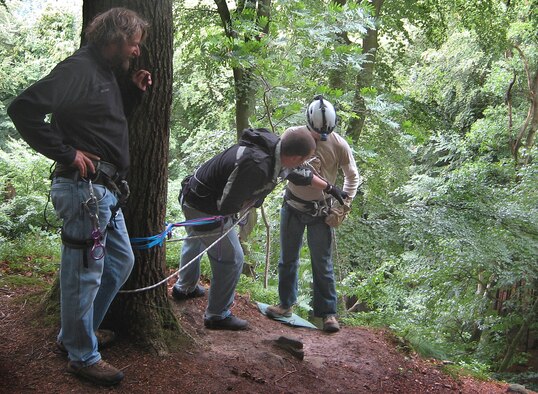 SPANGDAHELM AIR BASE, Germany -- Mike Kirsch, Outdoor Recreation program director, looks on as 2nd Lt. Vincent McLean, 52nd Logistics Readiness Squadron Materiel Management Flight commander and Outdoor Recreation volunteer, helps strap in a participant during a caving and rappelling daytrip in Luxembourg. After a 20-minute hike into the woods, about 25 Sabers crawled through caves and careened off cliffs and into caves while donning hard hats and harnesses. Additional Outdoor Recreation caving and rappelling trips are planned for Aug. 9 and Sept. 12. (U.S. Air Force photo by 1st Lt. Kathleen Polesnak)