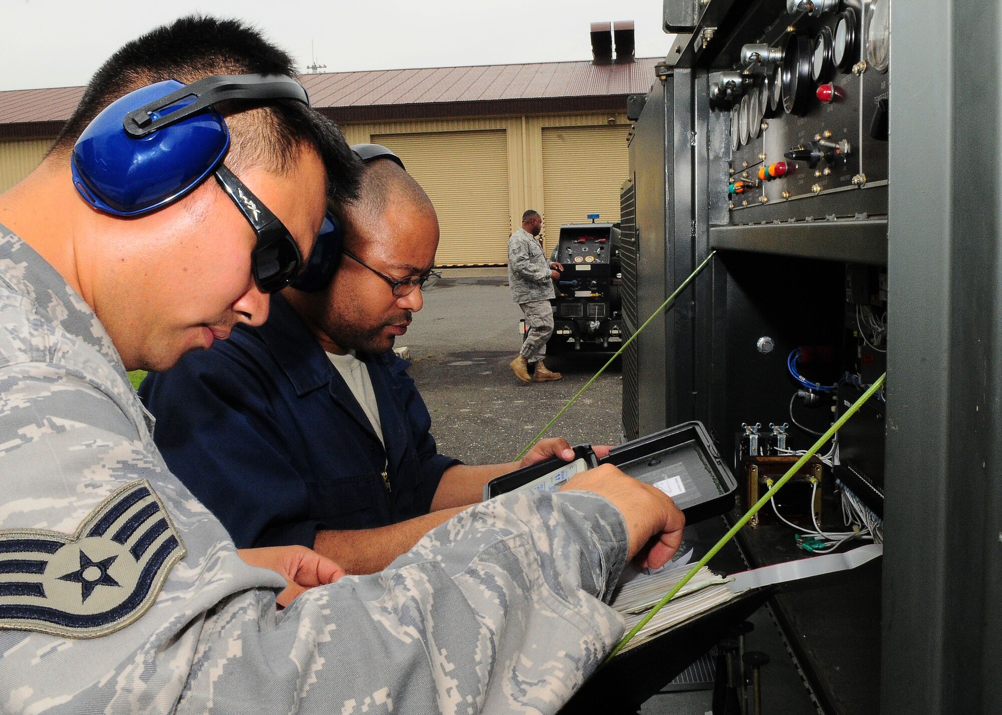 YOKOTA AIR BASE, Japan -- Staff sergeants Bretney Jones (right) and Gabriel Hayashi, 374th Maintenance Squadron Aerospace Ground Equipment Flight, troubleshoot a mobile air conditioner July 23. Members of the AGE flight support the base's flying mission by maintaining more than 600 pieces of ground support equipment. (U.S. Air Force photo/Airman 1st Class Michael Dillon)