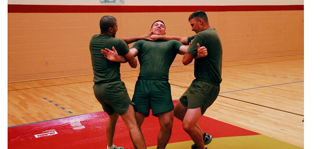 Military policemen Lance Cpl. Marc Sams, left, and Pfc. Kyle Darst practice a team takedown technique on fellow MP Lance Cpl. Josh Albert during training in the gym at the Marine Corps Air Station in Yuma, Ariz., July 28, 2009. The provost marshal’s office trained its MPs to control combative subjects by manipulating their momentum, body mechanics and leverage.