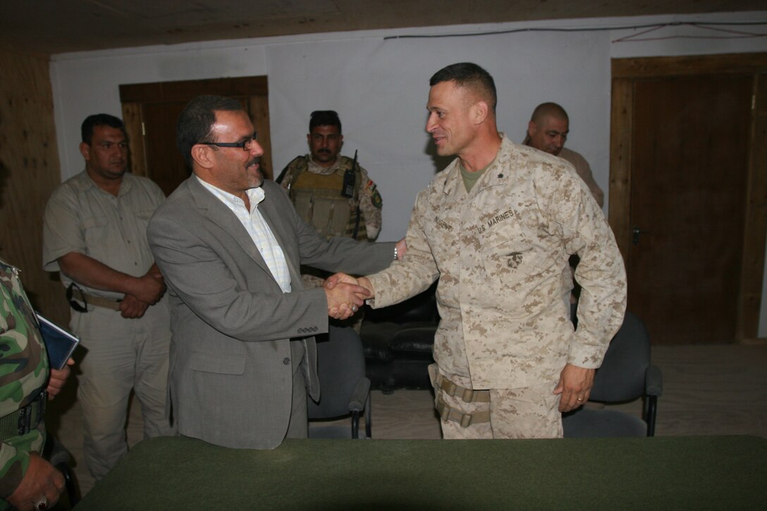 Lt. Col. Paul J. Nugent, commanding officer of 2nd Battalion, 1st Marine Regiment, Regimental Combat Team 8, and Sameer Alhaddad, receivership secretariat and prime minister’s representative for the Government of Iraq, shake hands after transferring Combat Outpost Rawah from Coalition forces to the Government of Iraq, July 29, 2009. The transfer of COP Rawah is a result of the progress Iraqi Security Forces have made in preserving peace and stability throughout Al Anbar province.