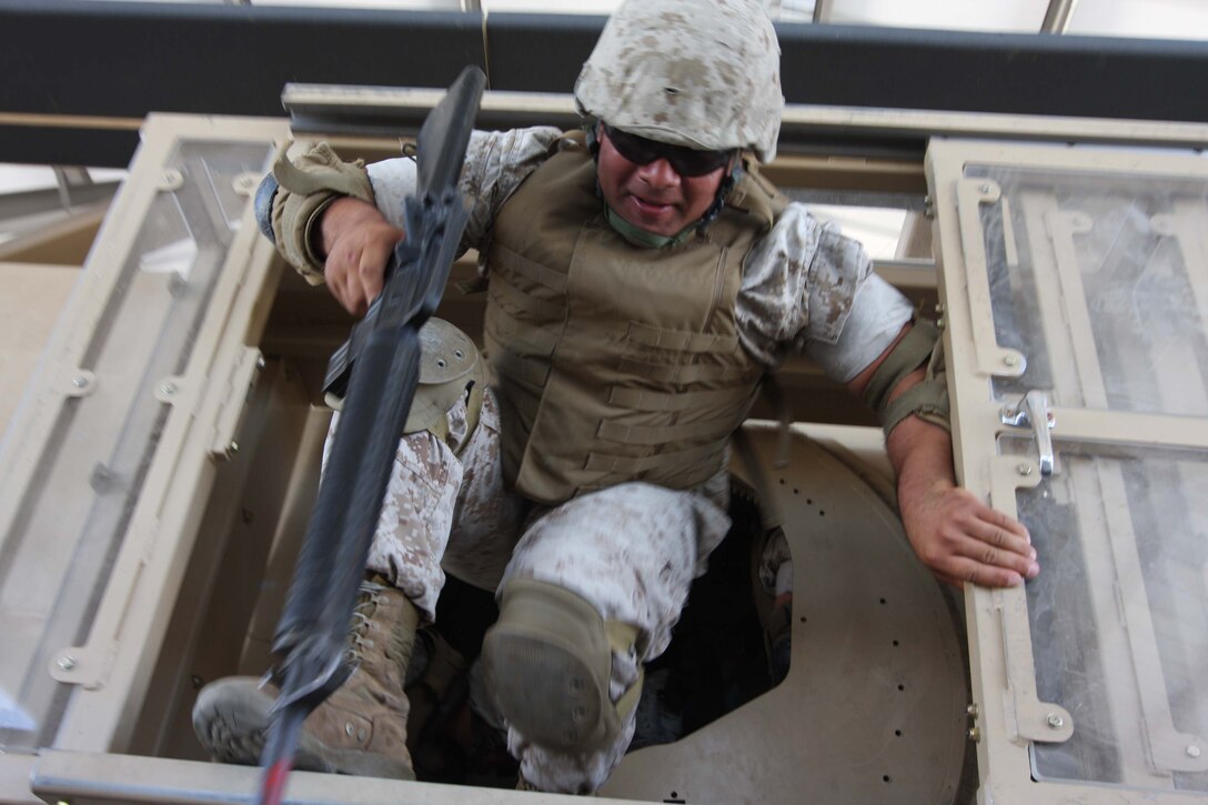 Lance Cpl. Ryan Romero, a motor transportation operator with Marine Wing Support Squadron 374, hops down from the gunner's hatch after participating in the Combat Center's newest rollover training simulator, the Mine Resistant Ambush Protected Egress Trainer, at the Battle Simulation Center at Camp Wilson July 30.