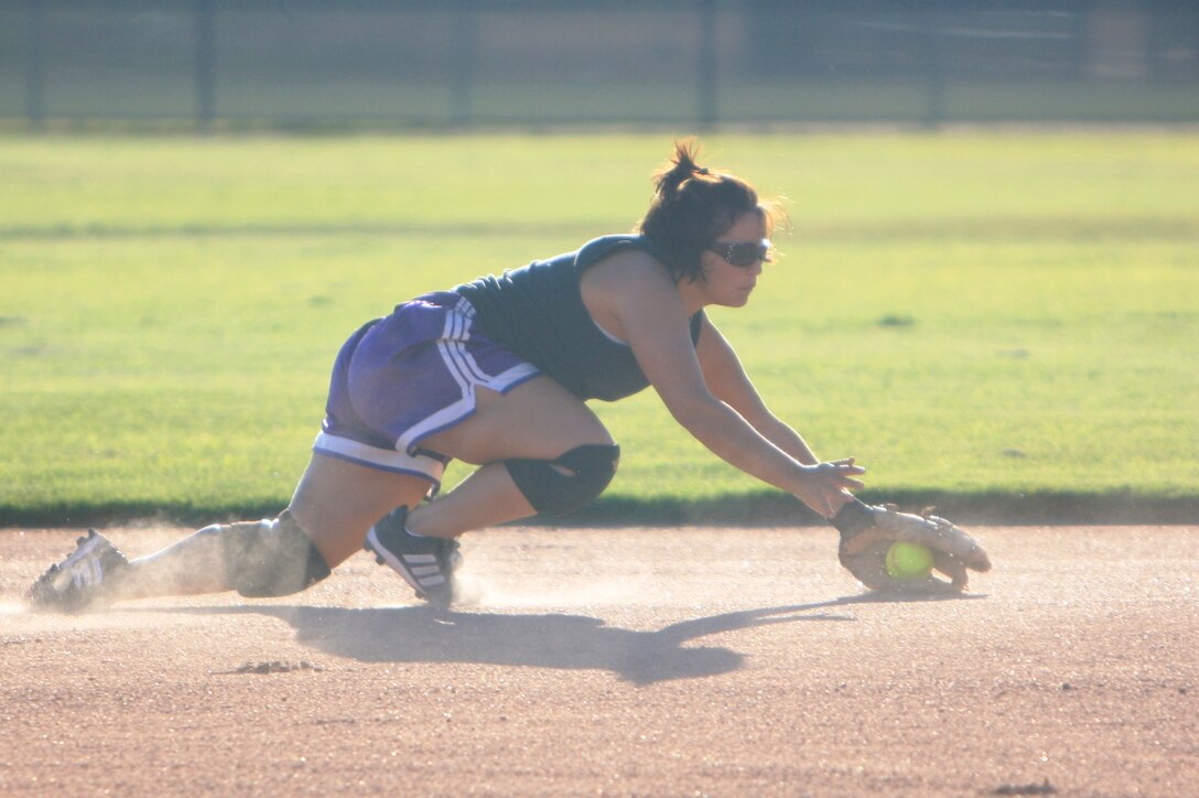 Lance Cpl. Katherine Smith, an administrative clerk at the Installation Personnel Administration Center, who played with the All-Marine Women’s Softball Team in 2007, dives as she grabs a ground ball while being screened Wednesday at Felix Field.