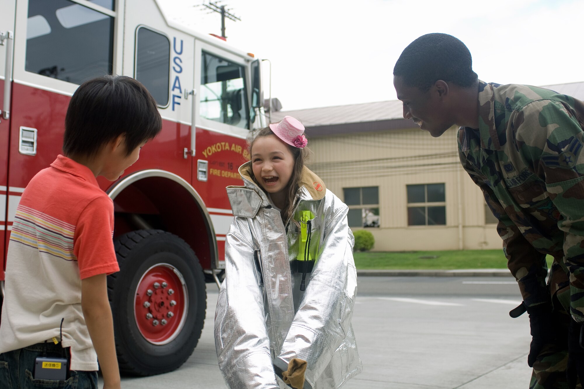 YOKOTA AIR BASE, Japan -- Airman 1st Class Taylor Manuel, 374th Civil Engineer Squadron firefighter, talks with the stars of TV Tokyo's children's television show "OHA, STA" during a visit to the base fire department July 29. Ariel Jasmin Bukowsky (center) helps Shion Kikuchi speak with various native English speakers during the show. Base firefighters gave the children an in-depth tour of fire trucks and even let the children try on fire-fighting gear. (U.S. Air Force photo/Osakabe Yasuo)