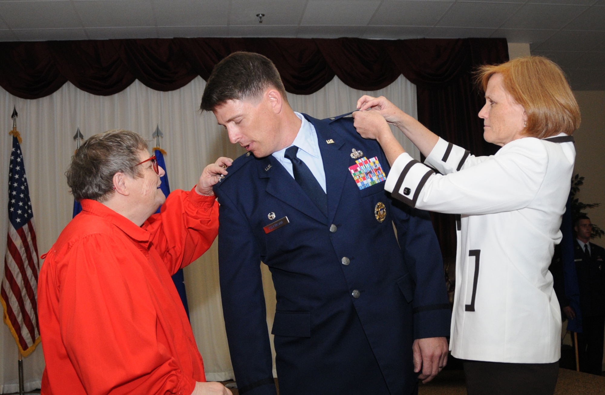 Brig. Gen. Brig. Ian Dickinson has his new rank pinned on by his mom, Sheila Dickinson, and his wife, JJ Dickinson, at his promotion ceremony at the Dragon's Lair, July 20.  The general is commander of the 81st Training Wing.  (U.S. Air Force photo by Kemberly Groue)